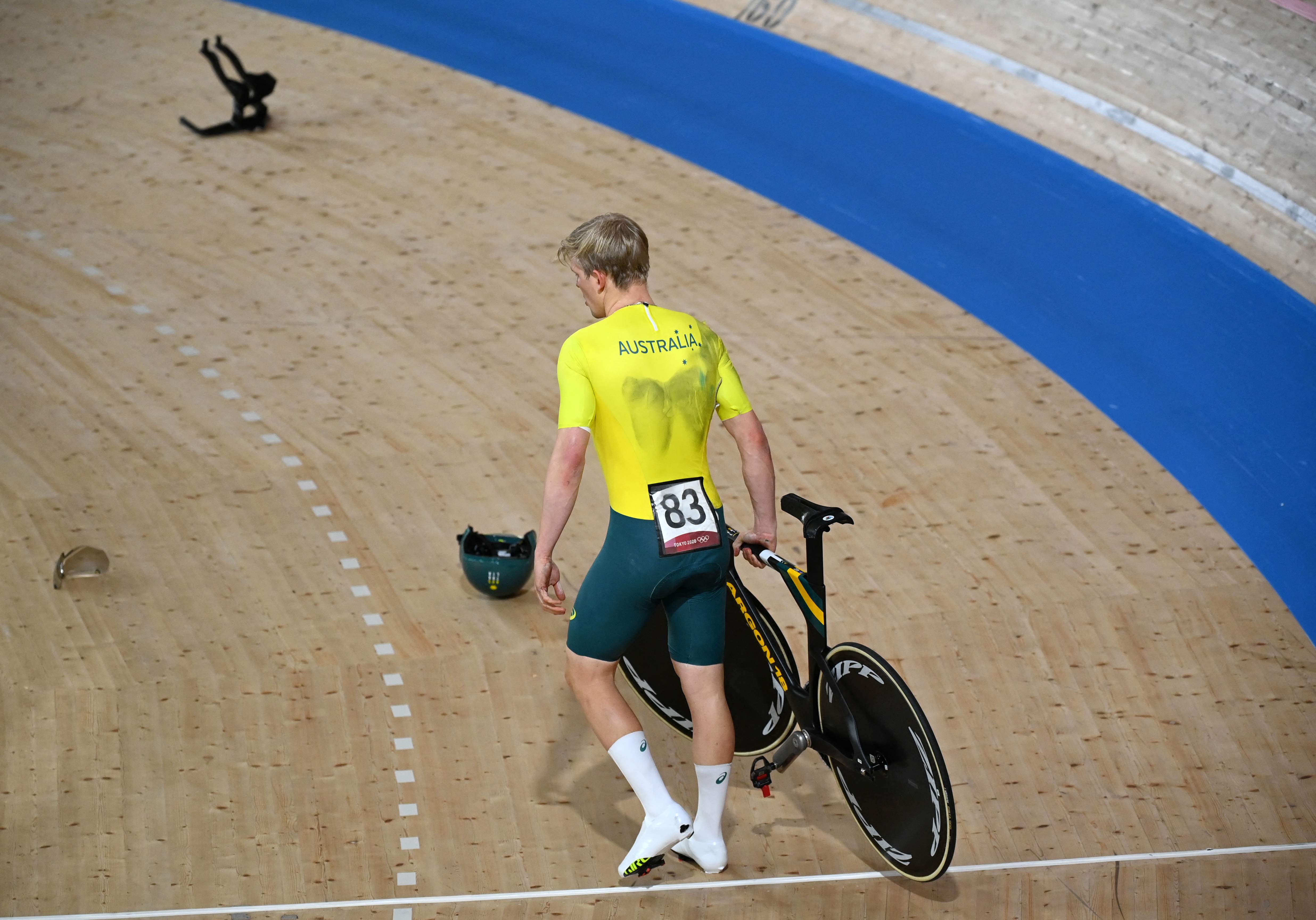 Alex Porter carries his bicycle after crashing