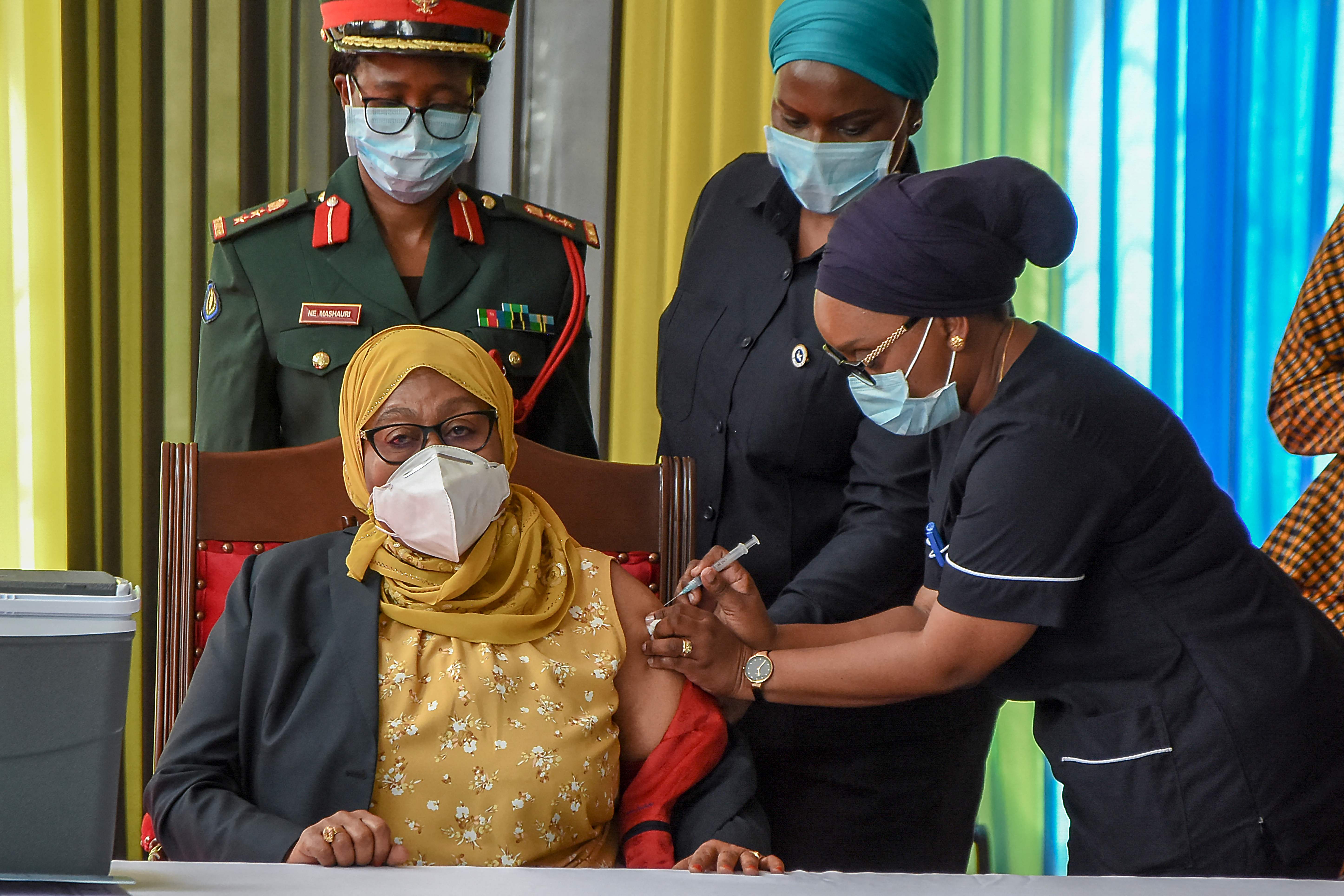 Tanzania's President Samia Suluhu Hassan (L) receives a shot of the Johnson & Johnson vaccine from a health worker at the State House in Dar es Salaam
