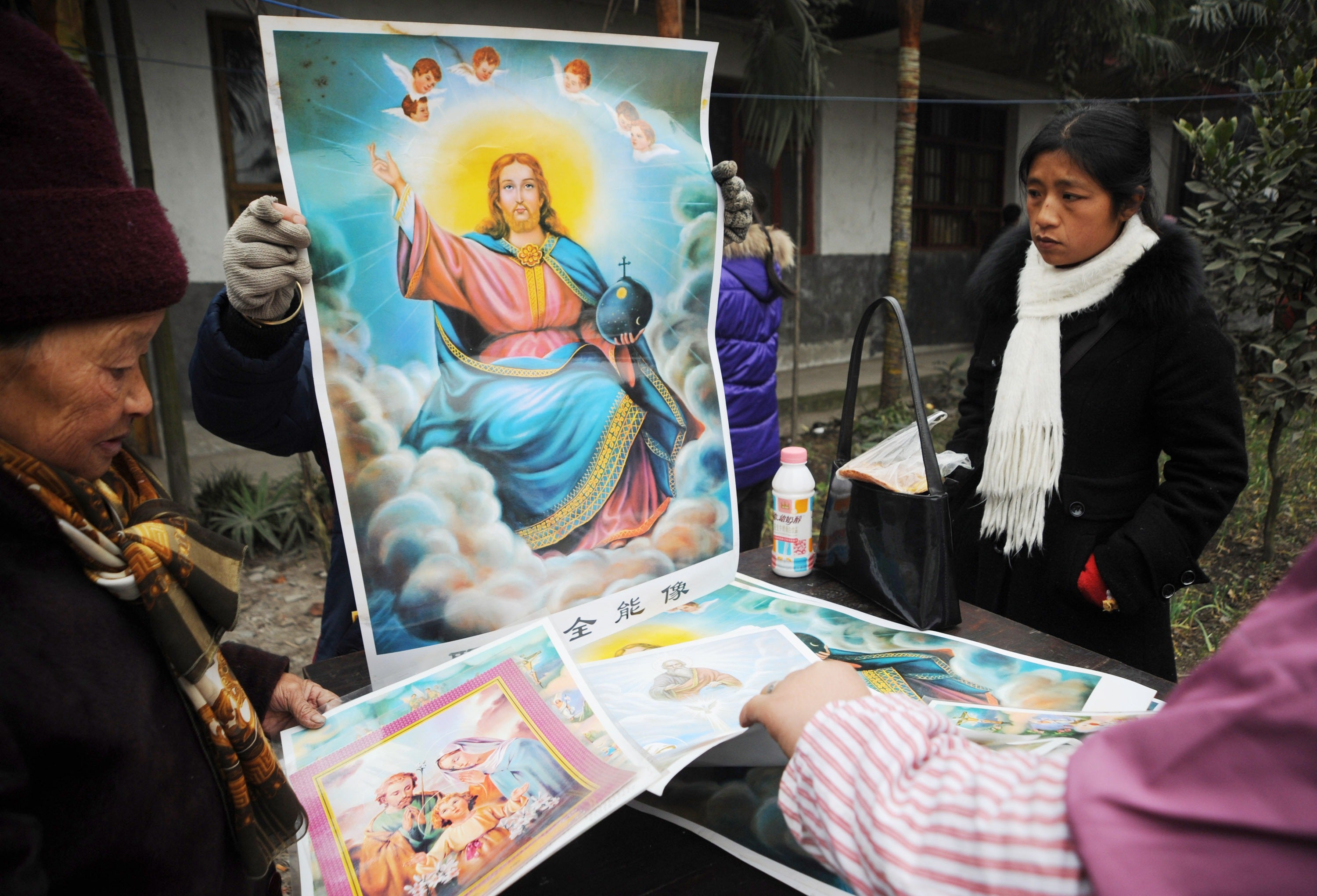 Catholics distribute pictures of Jesus before a Christmas Day mass at a church in Sichuan Province, China