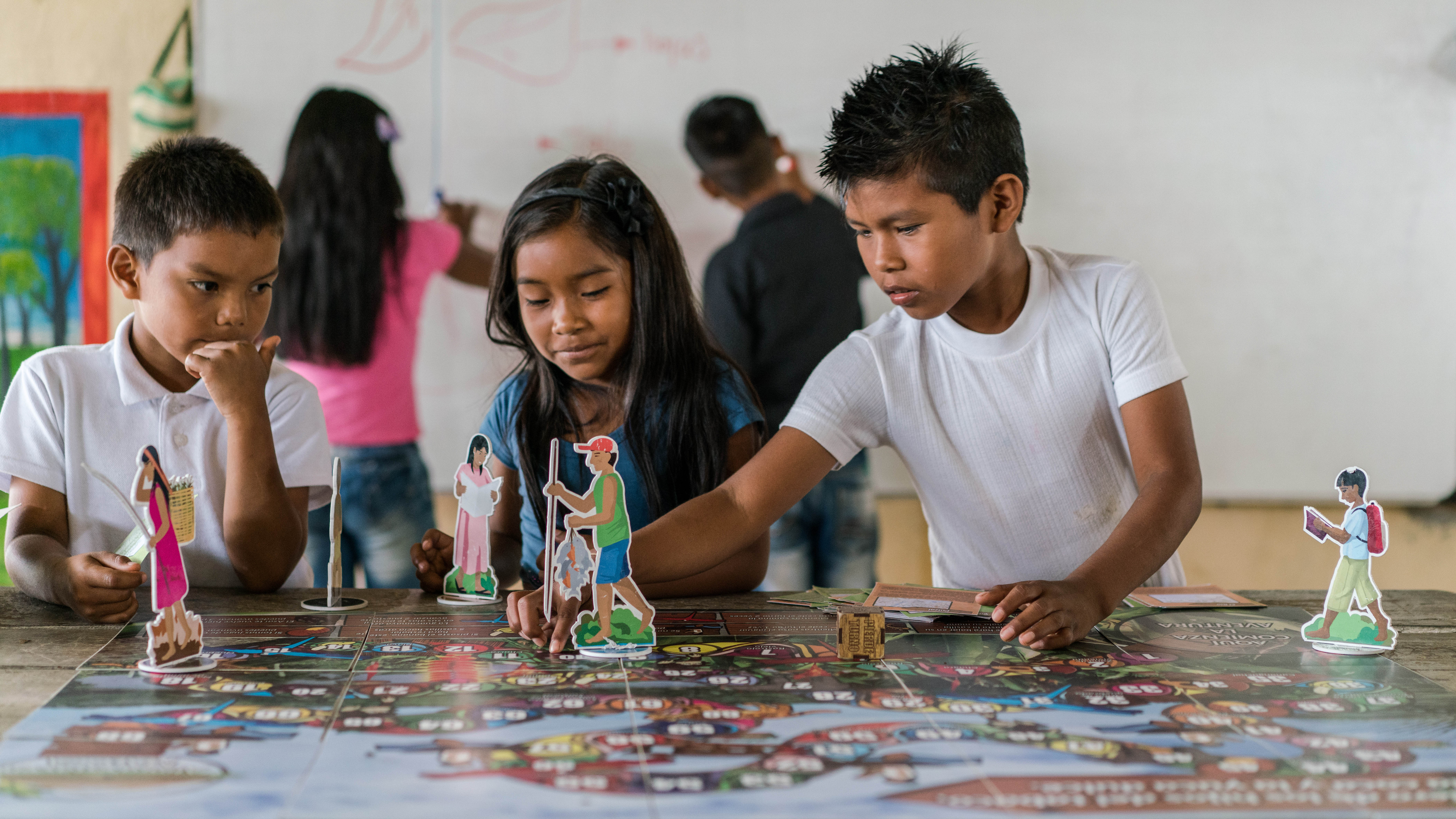 Children in class playing a board game specially developed to teach them the value of the forest, La Chorrera, Colombian Amazon