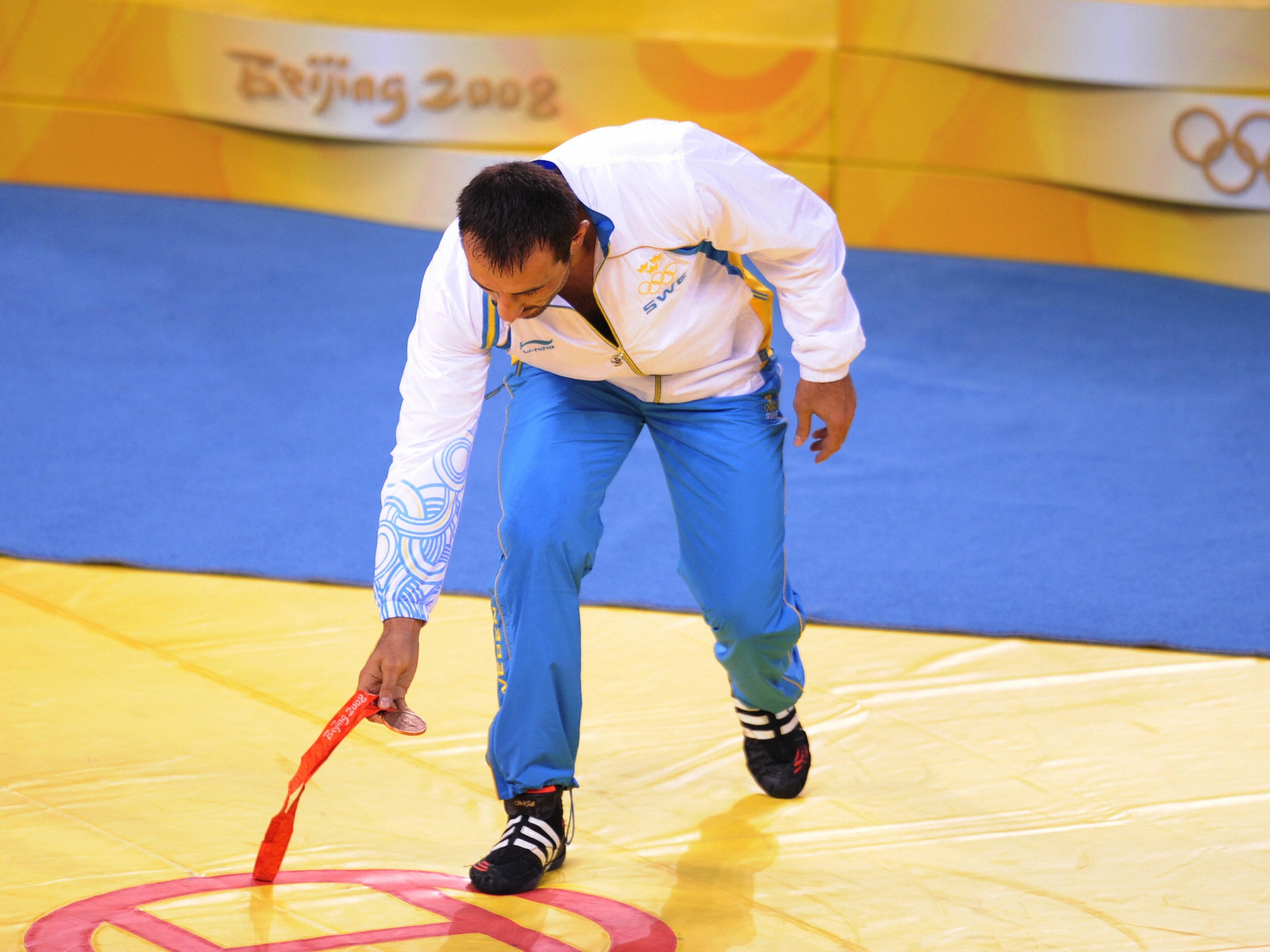 Greco-Roman wrestler Ara Abrahamian of Sweden places his bronze medal at the center of the competition mat in protest of the result in the men's Greco-Roman 84kg wrestling category during the 2008 Beijing Olympic Games