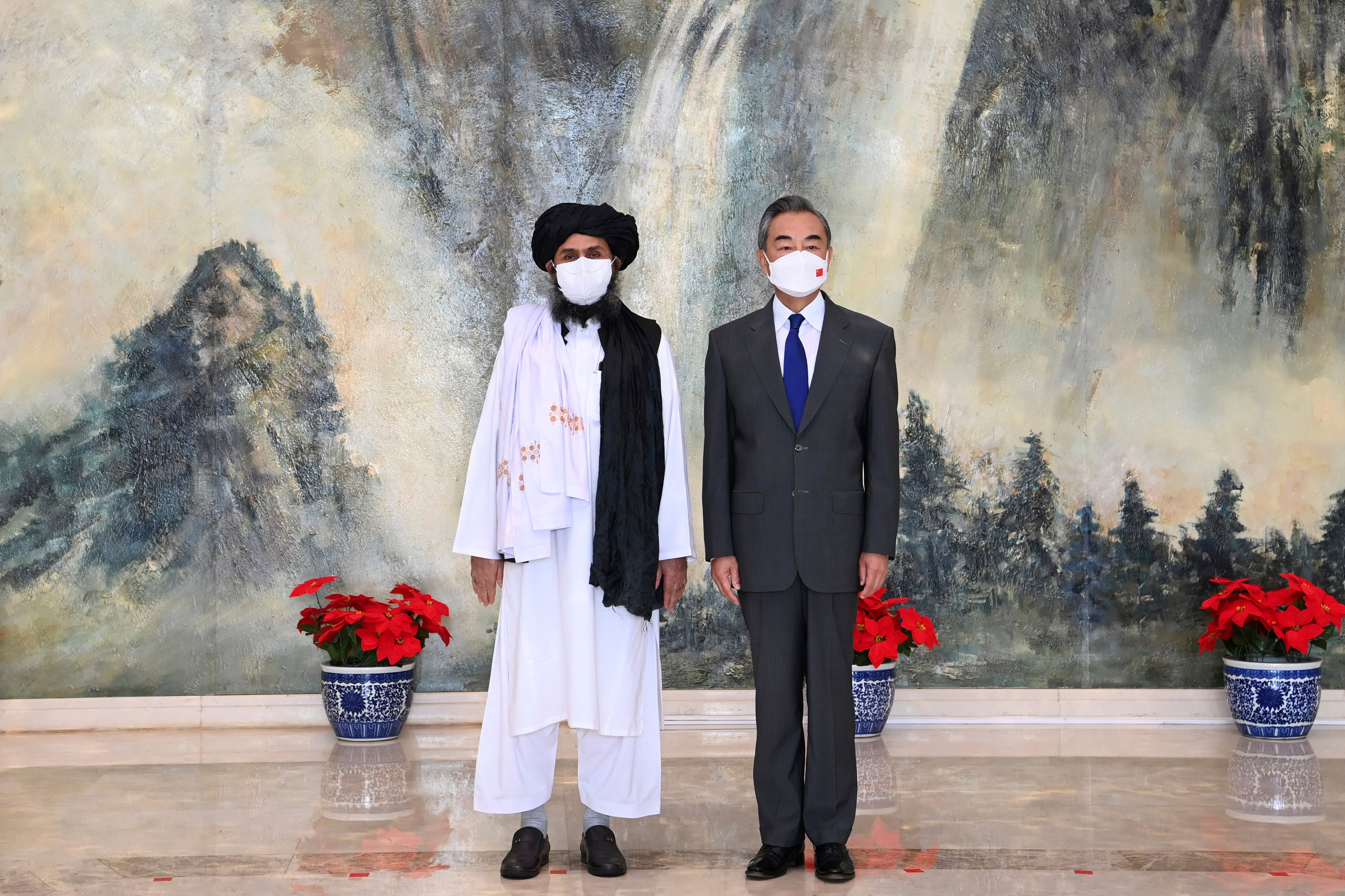 Taliban co-founder Mullah Abdul Ghani Baradar, left, and Chinese Foreign Minister Wang Yi, pose for a photo during their meeting in Tianjin, China