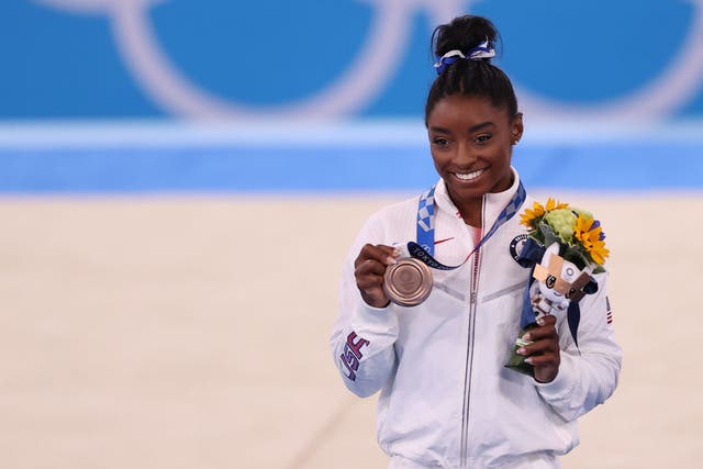 <p>Simone Biles poses with her bronze medal, won in the beam final at Tokyo 2020 on 3 August</p>