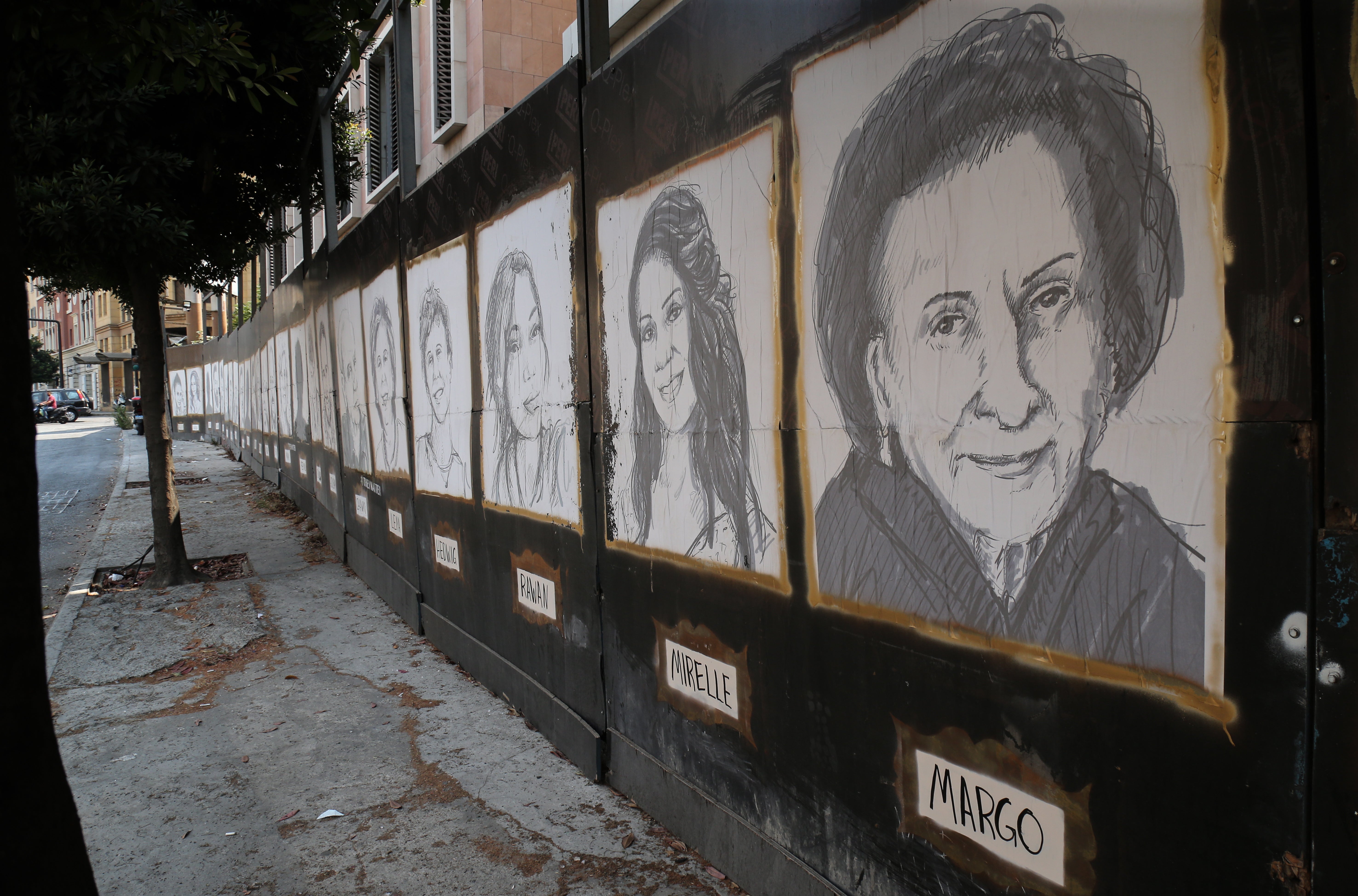 Sketches of victims of the port explosion hang on a wall in downtown Beirut