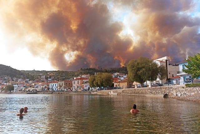 <p>Bathers watch flames burn on the mountain  on the island of Evia, about 160 kilometers (100 miles) north of Athens</p>