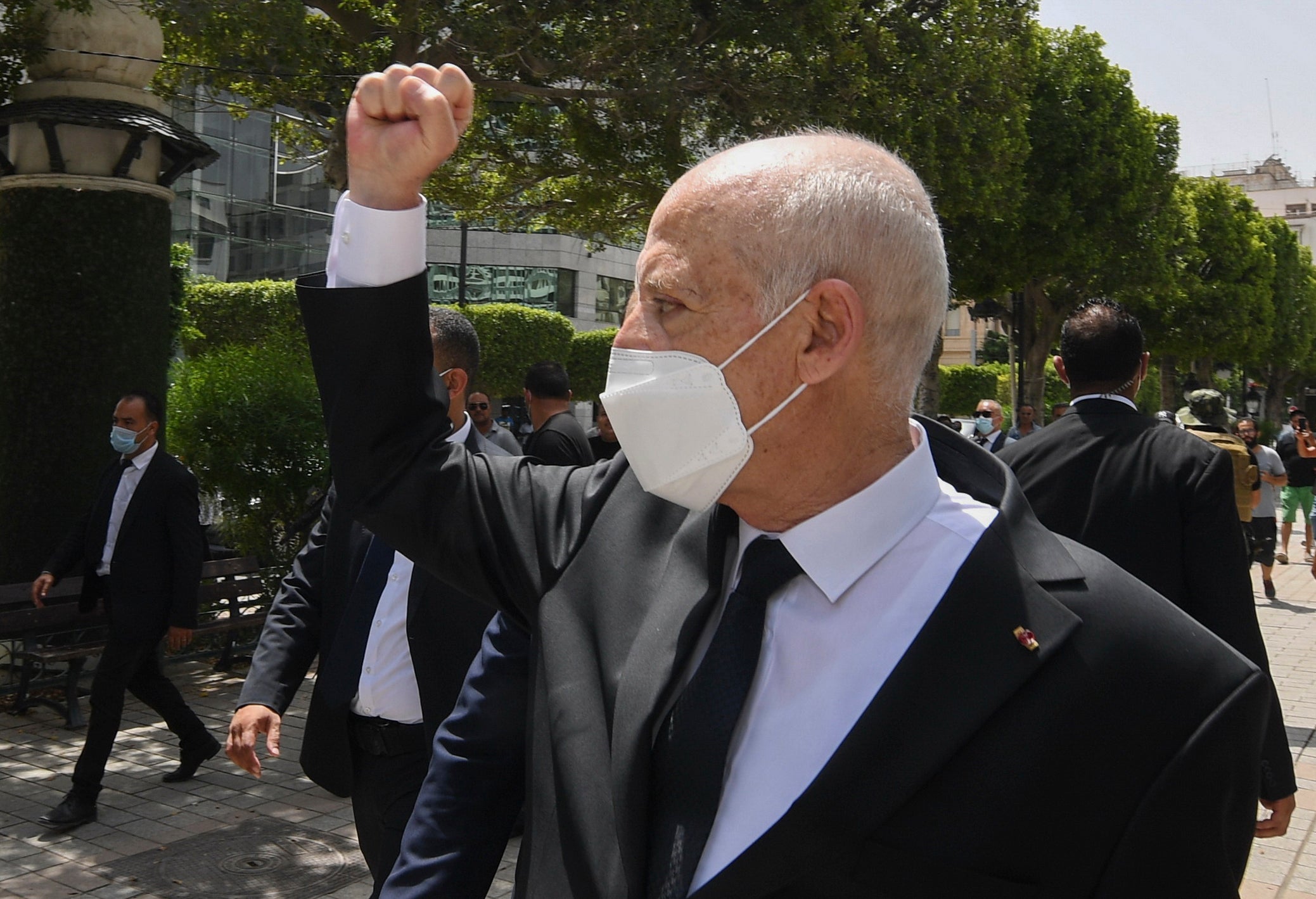 Tunisian President Kais Saied raises his fist to bystanders as he stroll along the avenue Bourguiba in Tunis