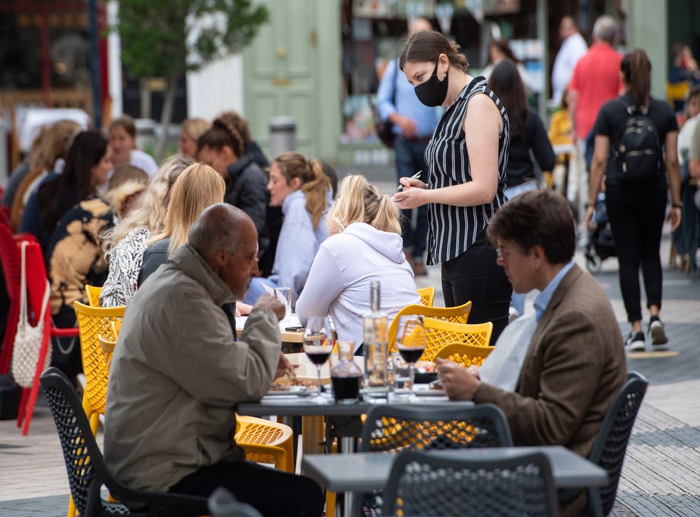 File photo dated 29/06/21 of a waitress wearing a face covering serving diners at outside tables in Kensington, London.