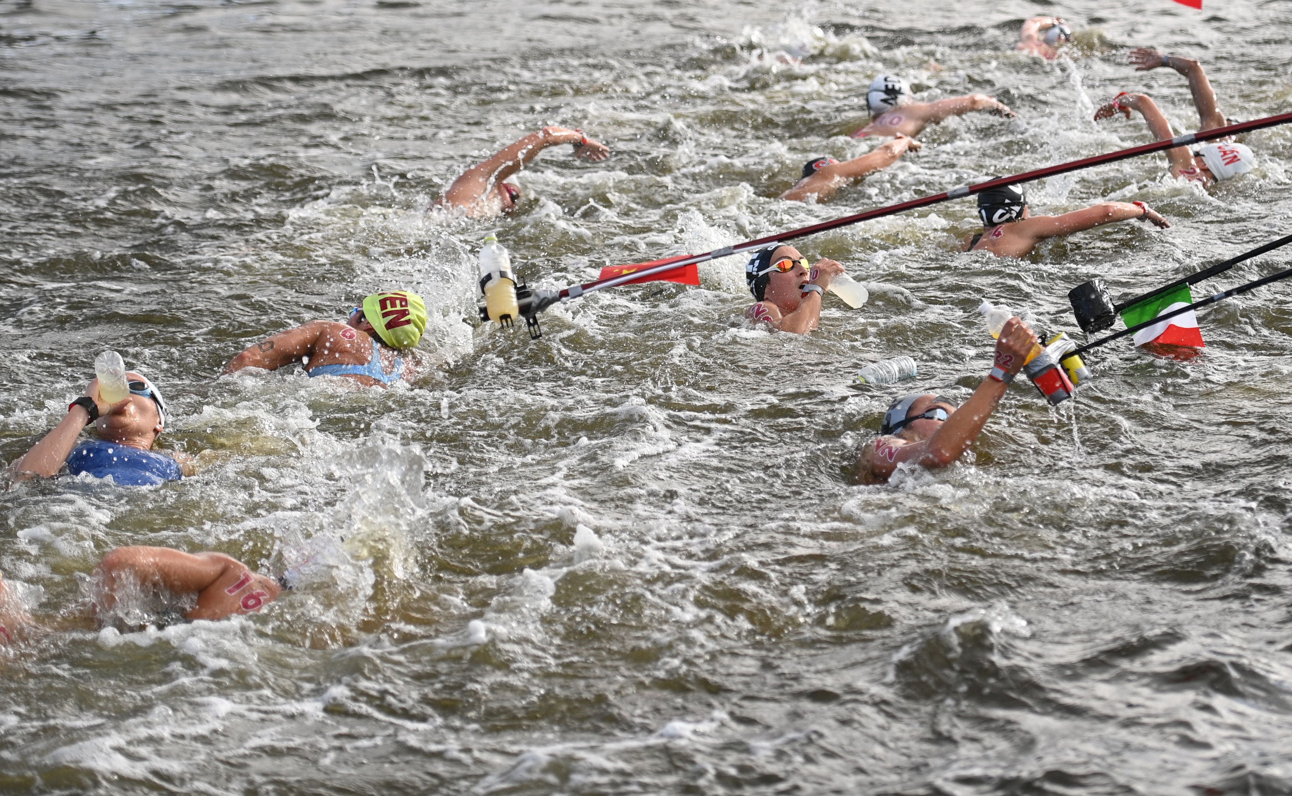 Competitors take refreshments at a feed station in the women's 10km marathon swimming event during the Tokyo 2020 Olympic Games at the Odaiba Marine Park in Tokyo on August 4, 2021.