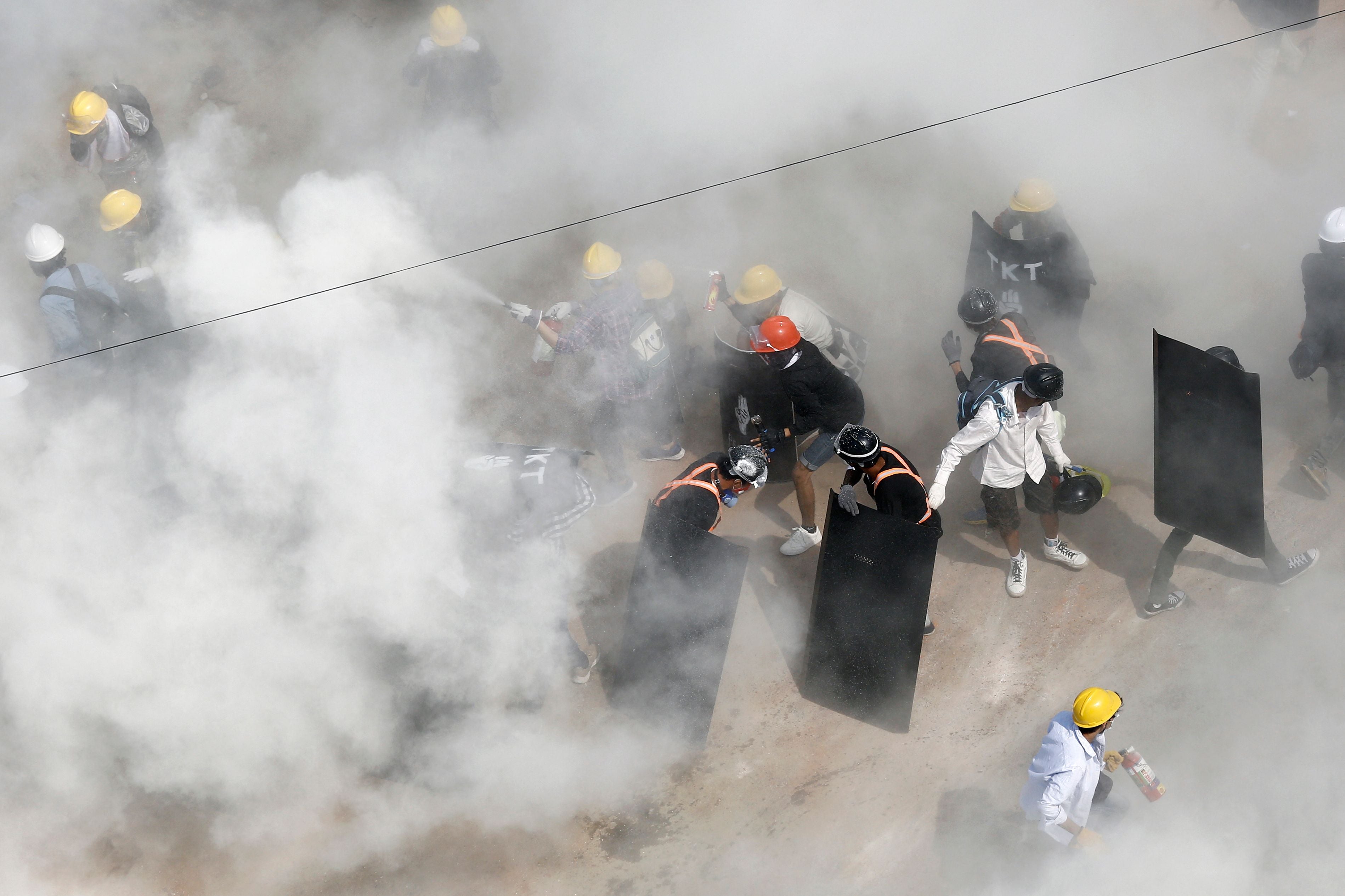 Protesters are engulfed by tear gas fired by police in a demonstration against the military coup