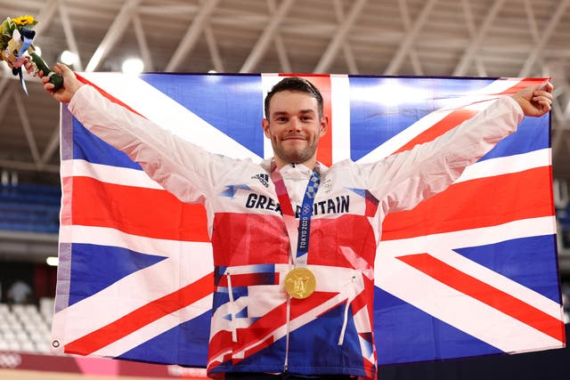 <p>Gold medalist, Matthew Walls of Team Great Britain, poses while holding the Great Britain flag</p>