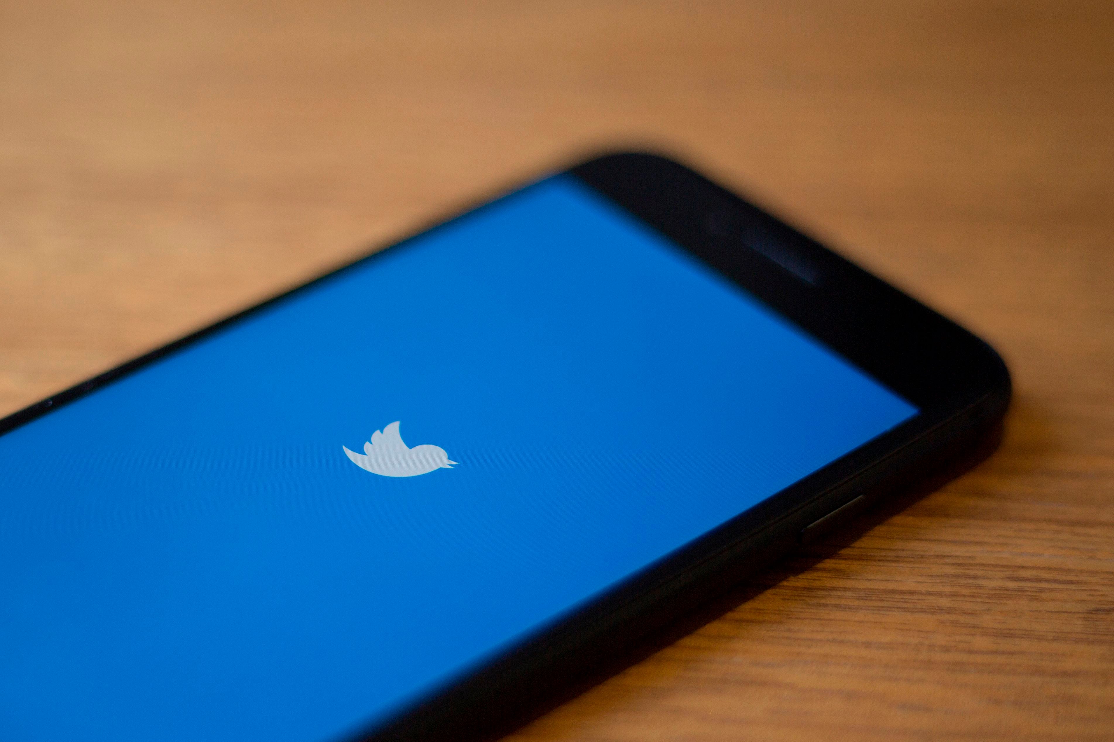 Twitter logo is seen on a phone in this photo illustration in Washington, DC