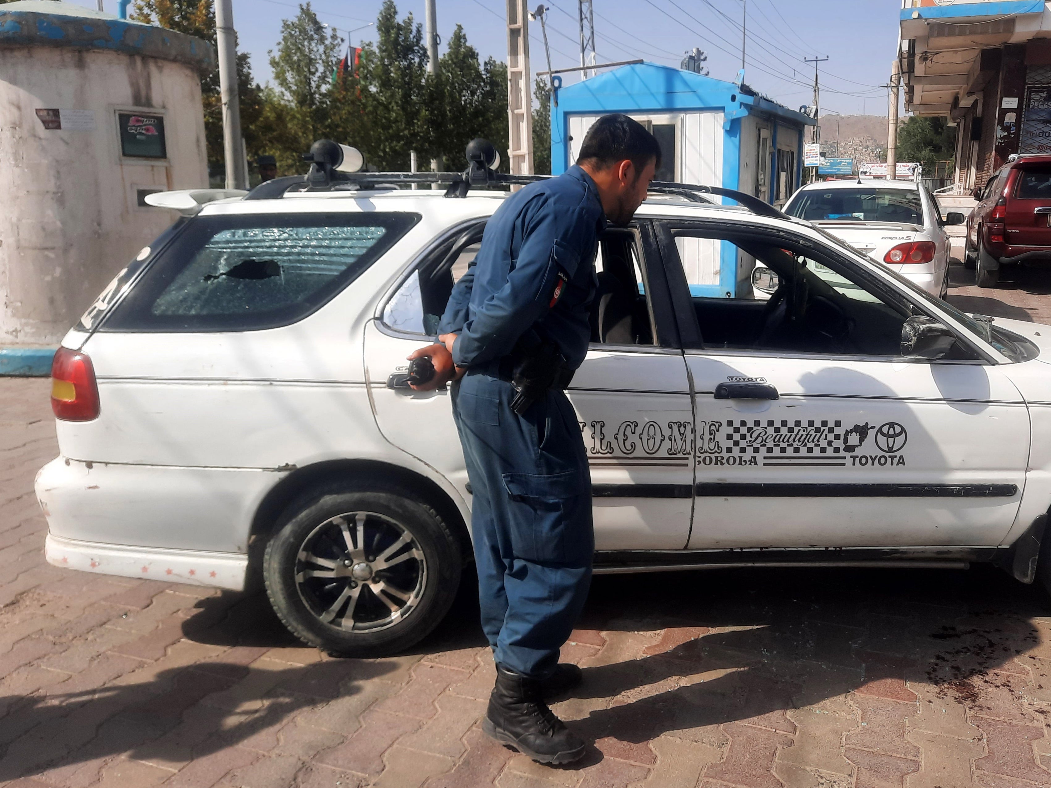 Afghan security officials inspect the scene of the assassination of Dawa Khan Menapal in Kabul