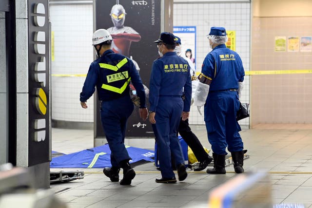 <p>Tokyo Fire Department personnel and a police investigator, right, move toward a platform at Soshigaya Okura Station after stabbing on a commuter train, in Tokyo Friday, Aug. 6, 2021.</p>