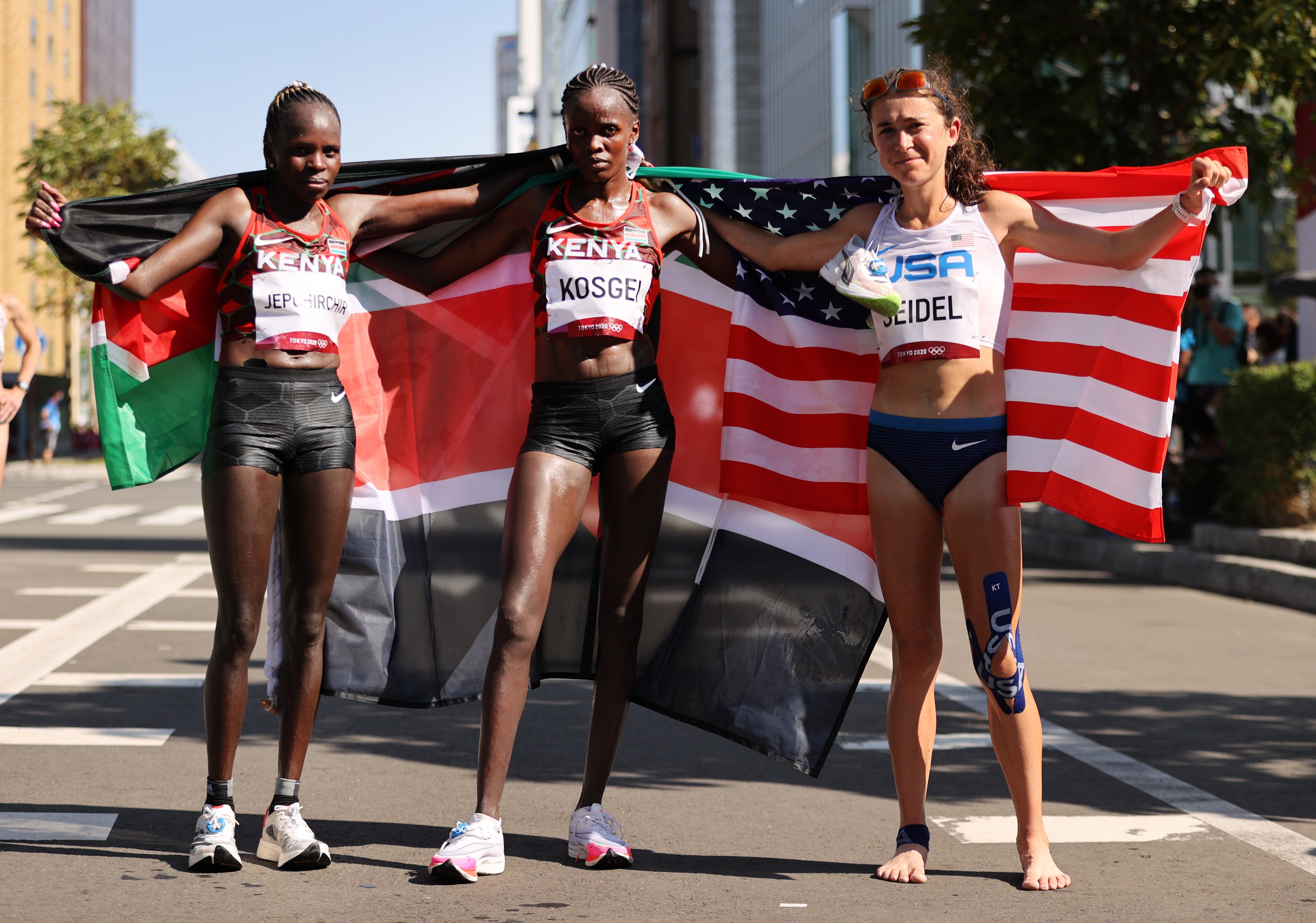 Gold medalist Peres Jepchirchir of Team Kenya, silver medalist Brigid Kosgei of Team Kenya and bronze medalist Molly Seidel of Team United States pose for photos after finishing the Women's Marathon Final on day fifteen of the Tokyo 2020 Olympic Games