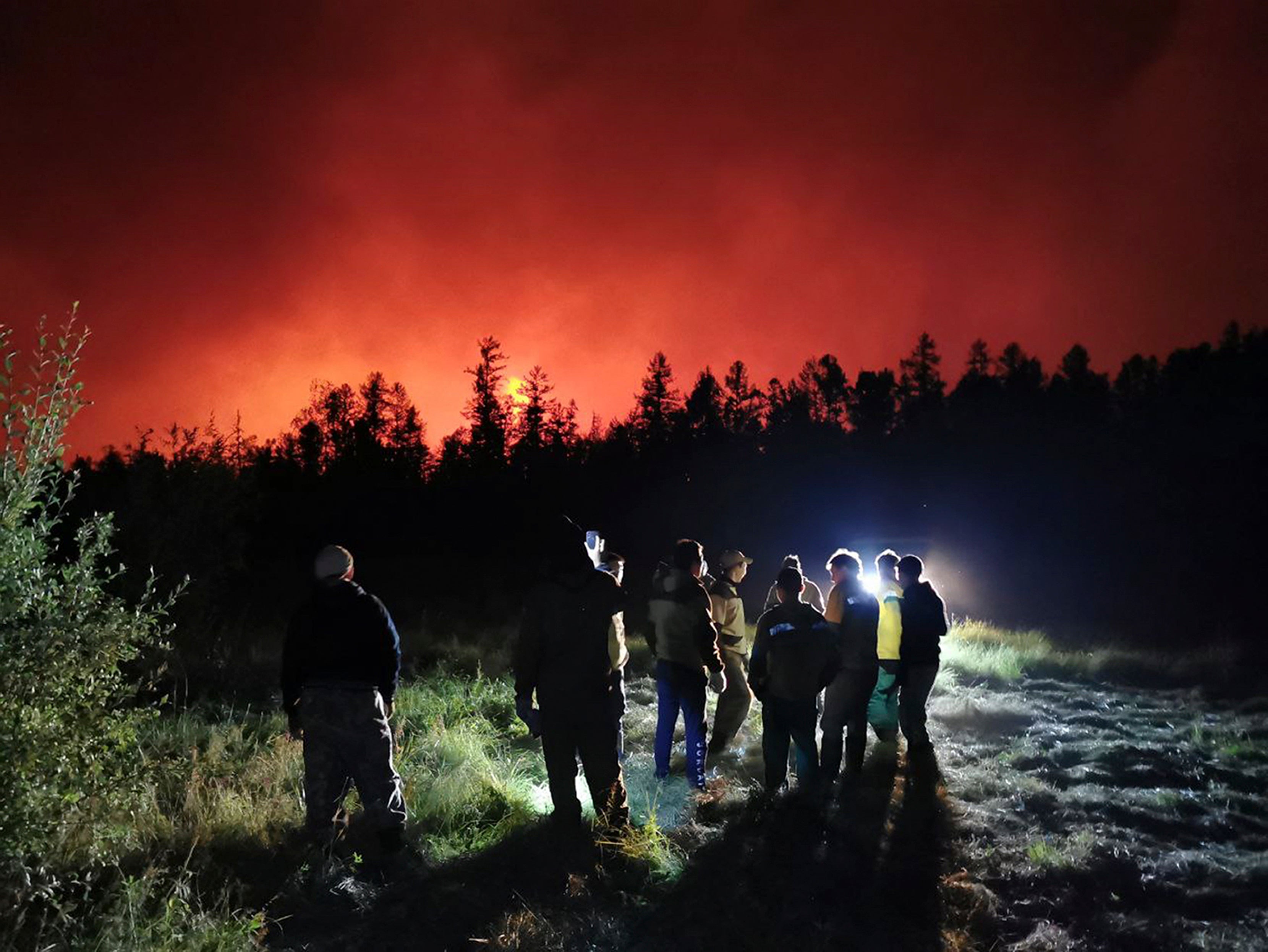 Firefighters and volunteers have a briefing as they work at the scene of forest fire at Gorny Ulus