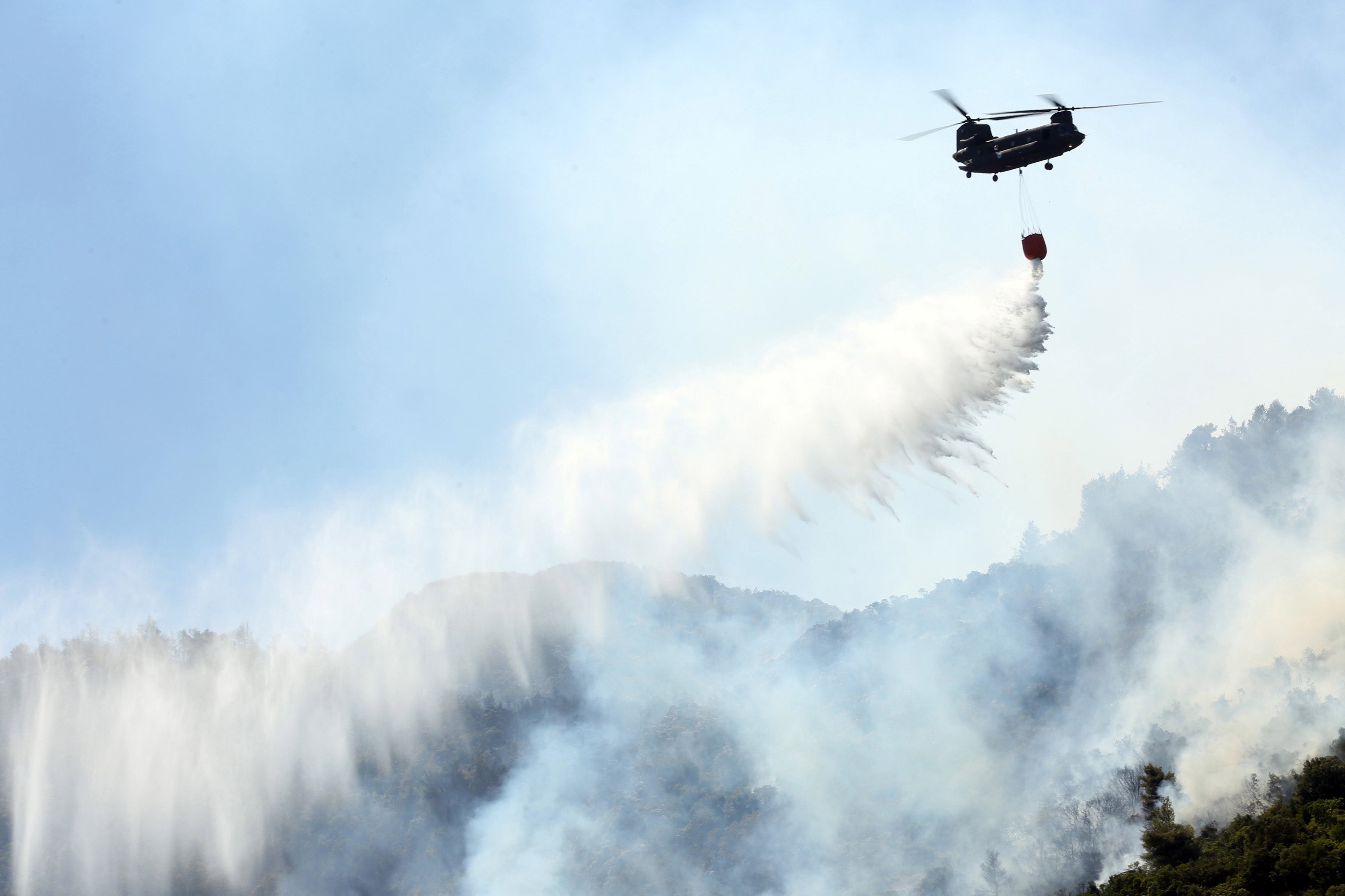 A Chinook douses a wildfire in the Malakassa area