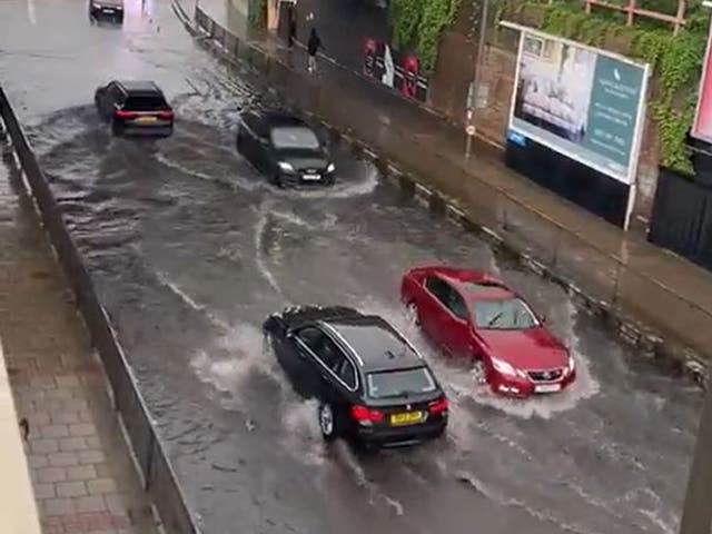 <p>Cars drive through flooding on Queenstown Road in Battersea after heavy rain in London on Saturday</p>