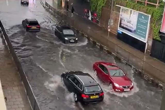 <p>Cars drive through flooding on Queenstown Road in Battersea after heavy rain in London on Saturday</p>
