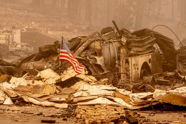 <p>An American flag is placed on a burned fire engine at a burned fire station in downtown Greenville, California, on Saturday</p>