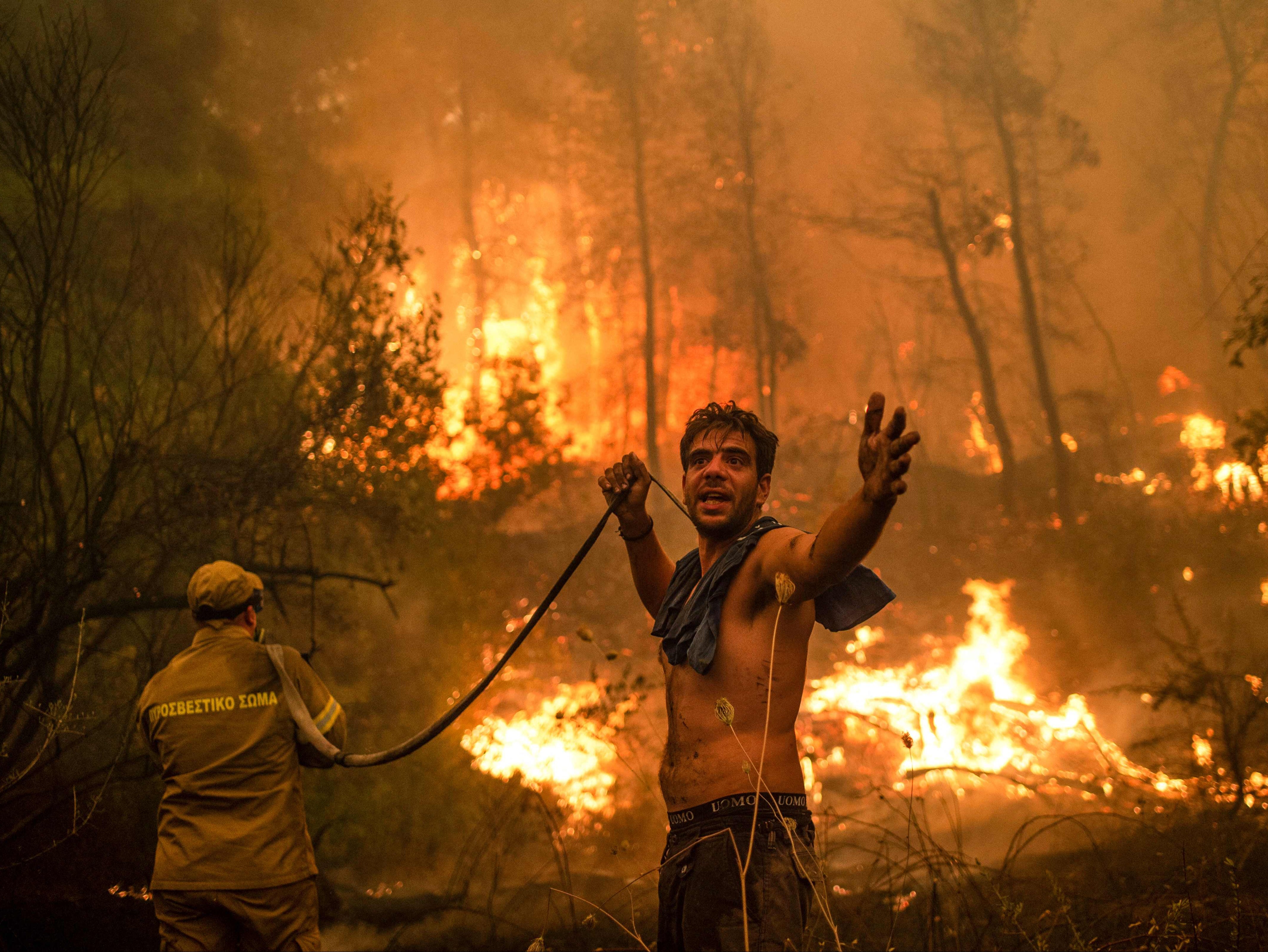 A local resident on the Greek island of Evia holds a water hose during catastrophic wildfires in August