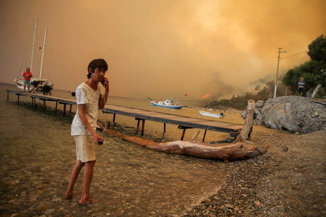 <p>People on the beach of smoke-engulfed Mazi</p>