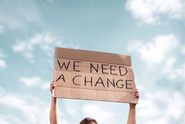 <p>Woman holding a banner of 'We Need A Change' during a protest about climate change </p>