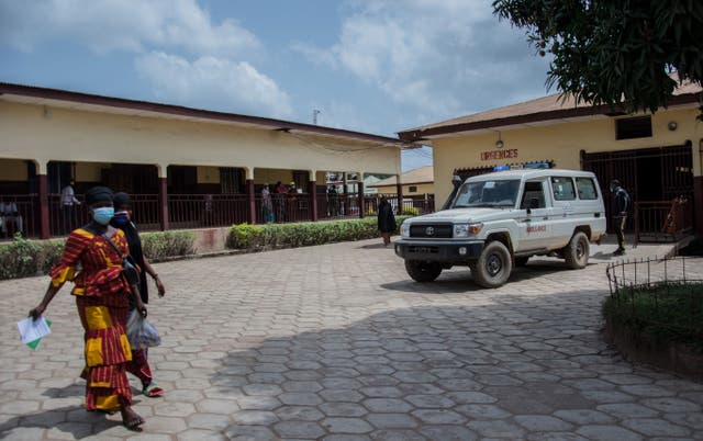 <p>Two women walk through the emergency drop-off area at the N’zerekore Hospital where the first cases of Ebola were found at the end of January 2021</p>