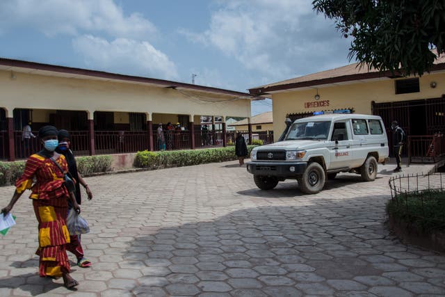 <p>Two women walk through the emergency drop-off area at the N’zerekore Hospital where the first cases of Ebola were found at the end of January 2021</p>