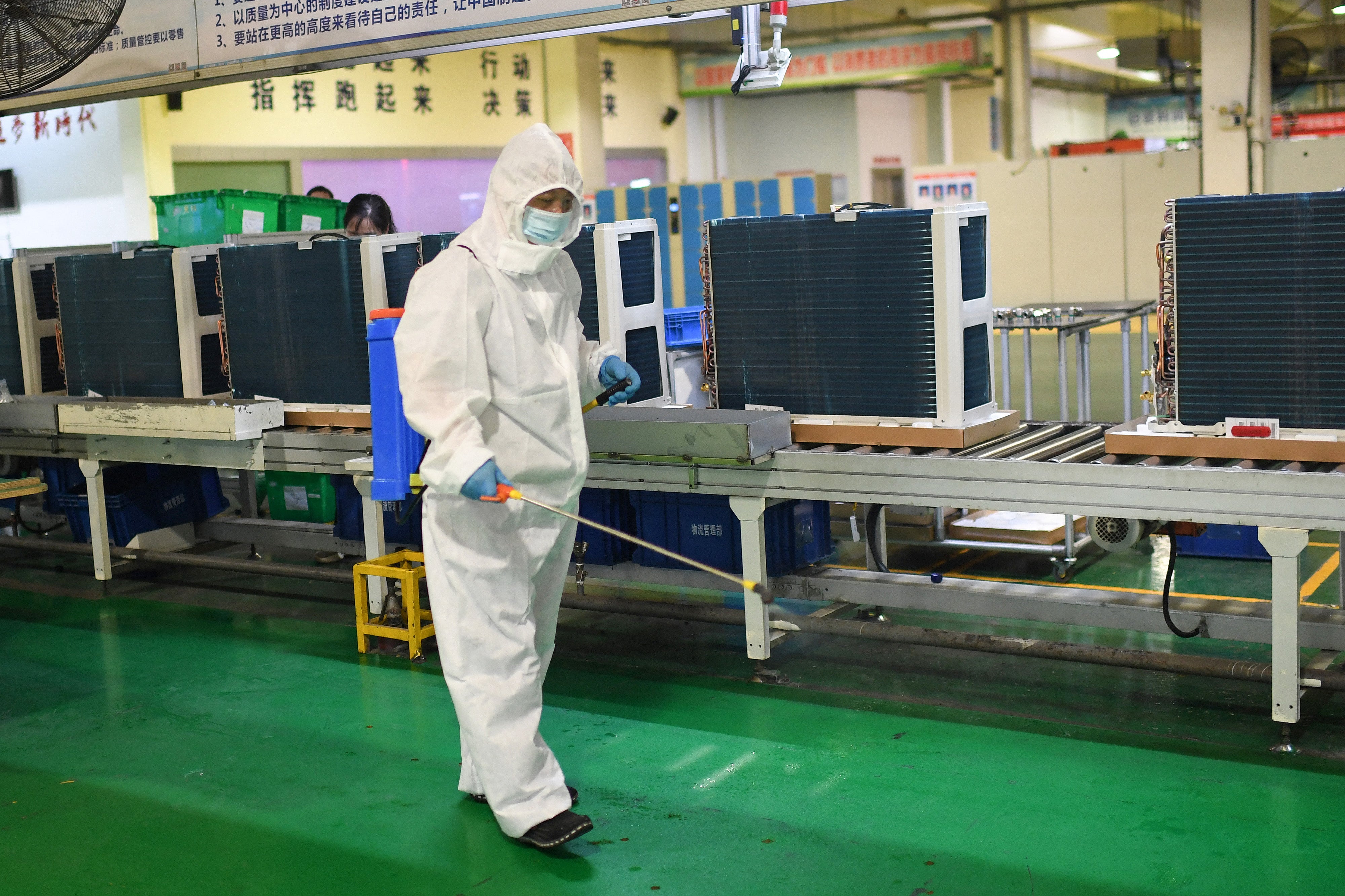 This photo taken on 9 August 2021 shows an employee wearing personal protective equipment spraying disinfectant as part of Covid-19 measures at a factory in Wuhan, in China's central Hubei province