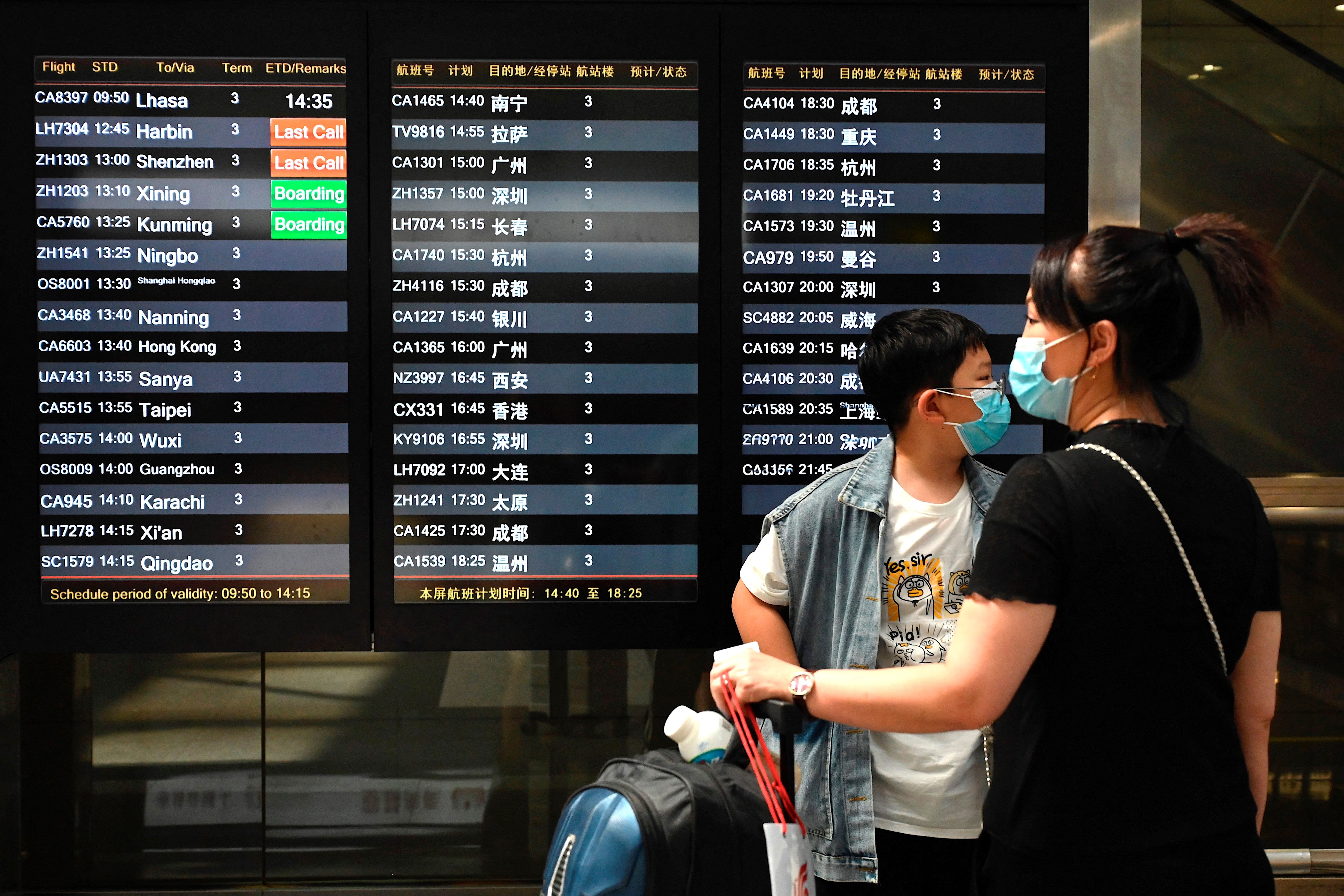 File: Travellers wearing face masks wait in front of a departures board at Beijing’s international airport on 10 August 2021