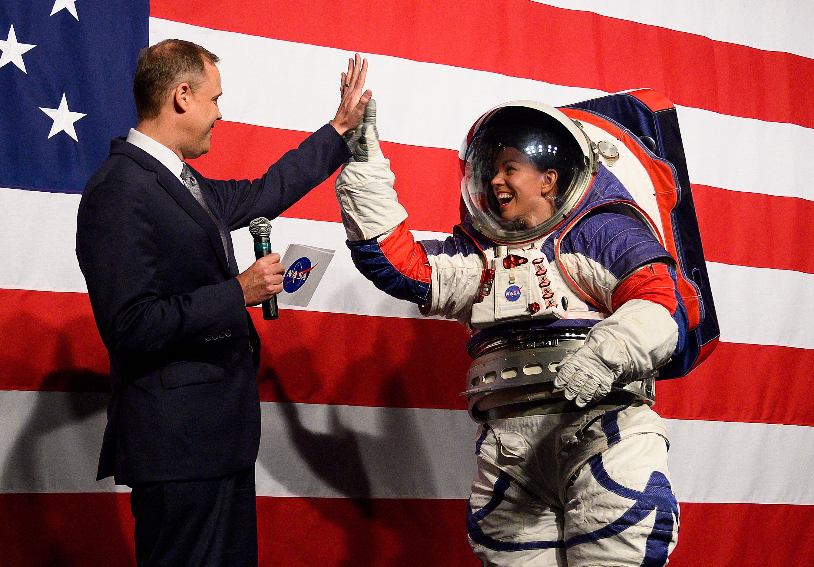NASA administrator Jim Bridenstine (L) welcomes Advance space suit engineer, Kristine Davis (R), to the stage during a press conference displaying the next generation of space suits as parts of the Artemis program in Washington, DC on October 15, 2019
