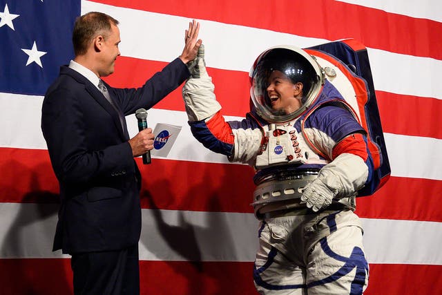 <p>NASA administrator Jim Bridenstine (L) welcomes Advance space suit engineer, Kristine Davis (R), to the stage during a press conference displaying the next generation of space suits as parts of the Artemis program in Washington, DC on October 15, 2019</p>