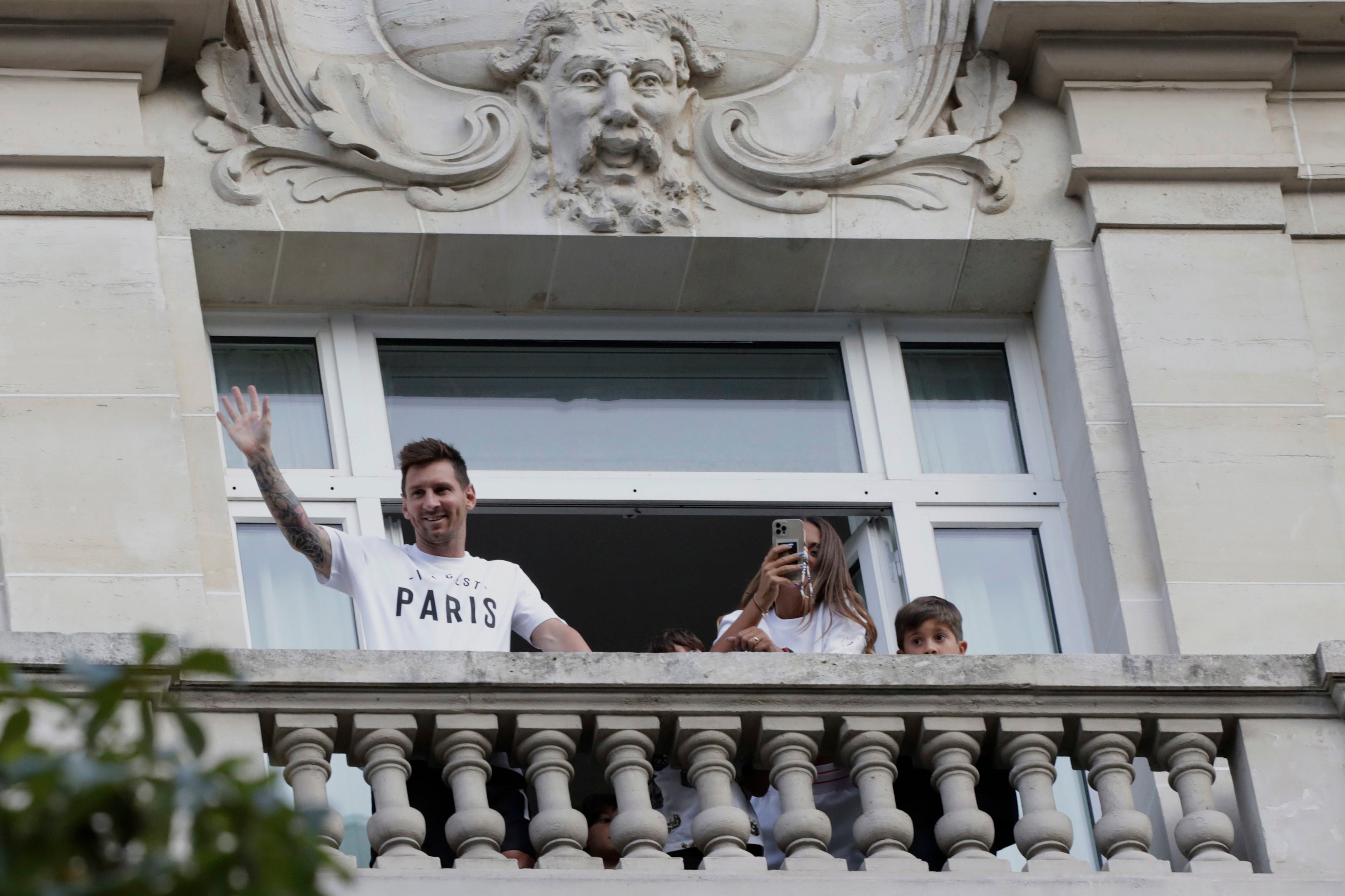 Lionel Messi, who has completed his move to Paris St Germain, waves to supporters from his hotel balcony (Adrienne Surprenant/AP).