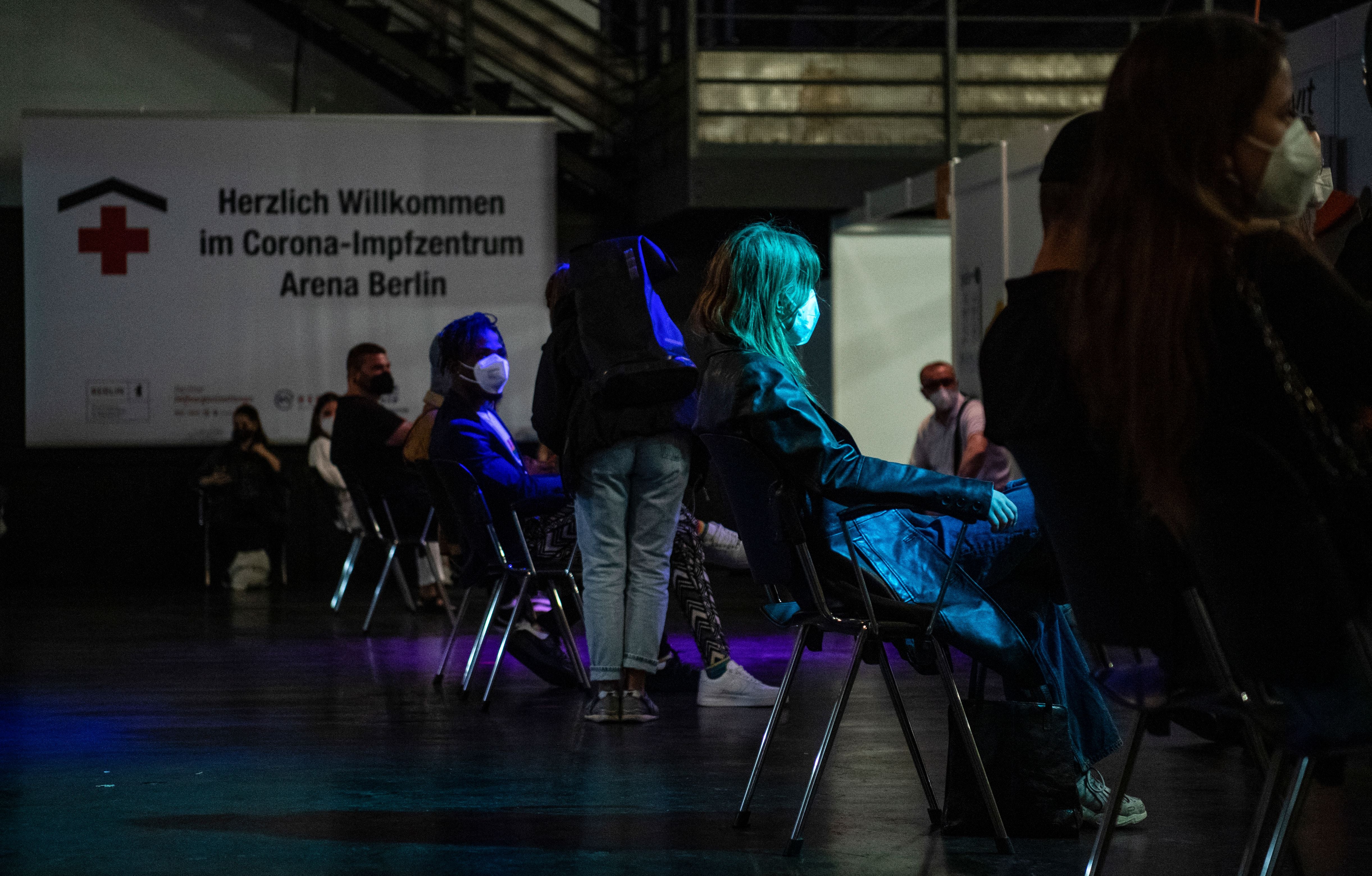 People wait to receive a Covid-19 vaccination shot at the Arena Treptow vaccination centre in Berlin on 9 August, 2021, during a so-called “Long Night of Vaccination” which featured local DJs spinning tunes for attendees until midnight. - A German nurse is suspected of replacing Covid vaccines with saline solution.