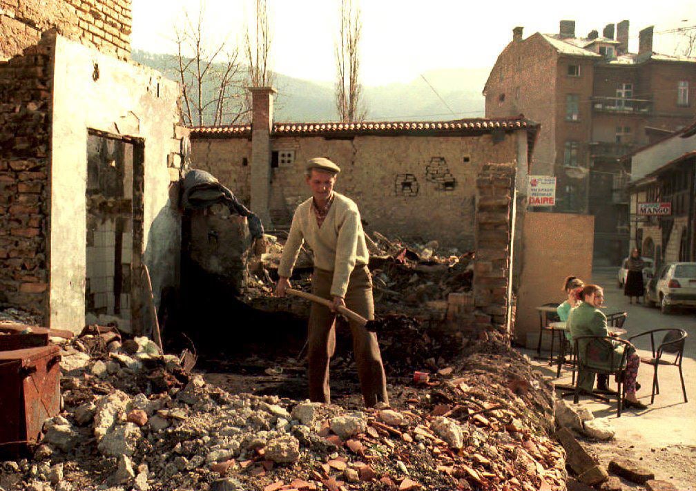 A Bosnian man cleans up the rubble of a destroyed house in Sarajevo, 12 March 1994