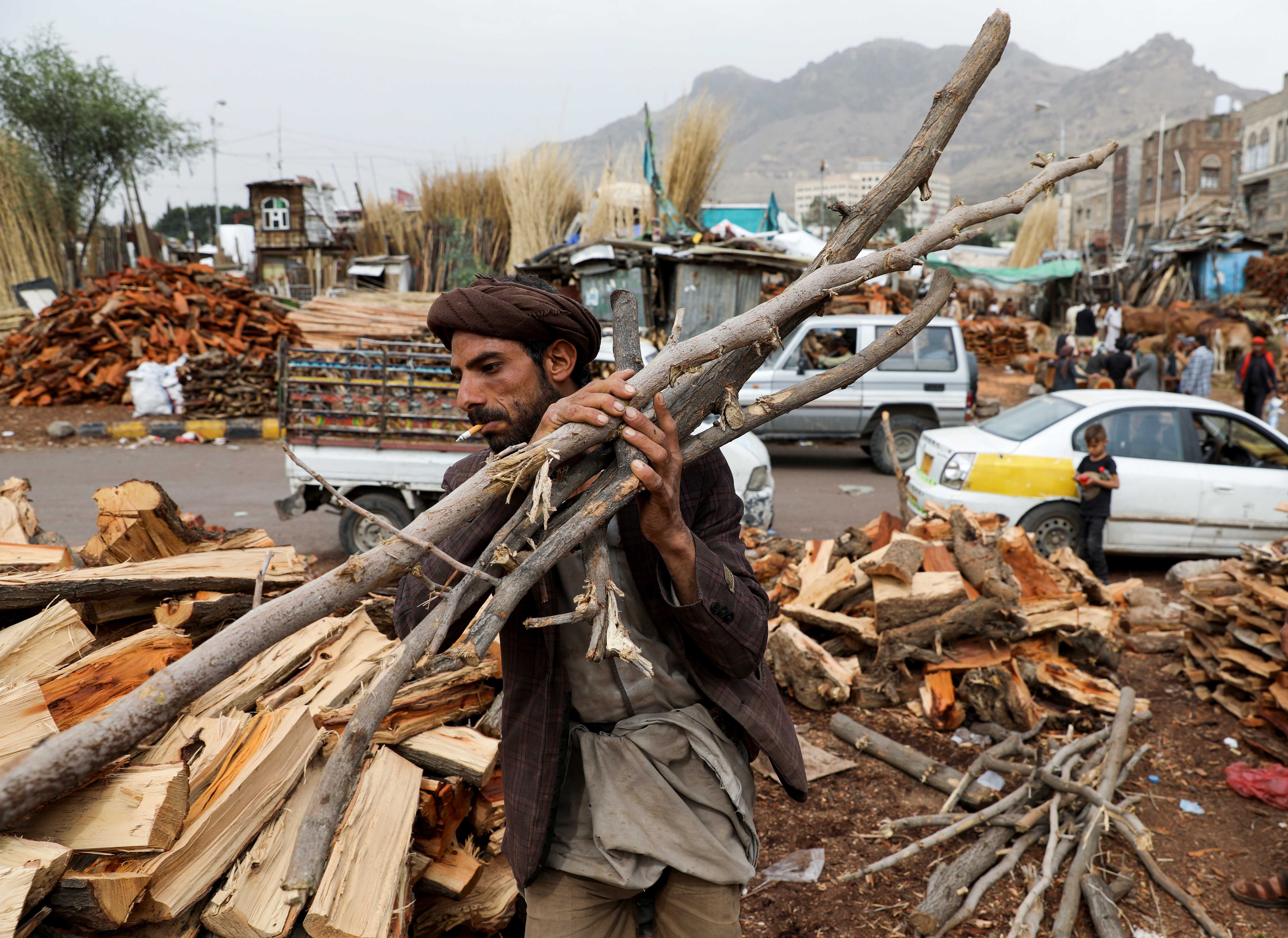 A vendor carries wood at a firewood market in the capital Sana’a
