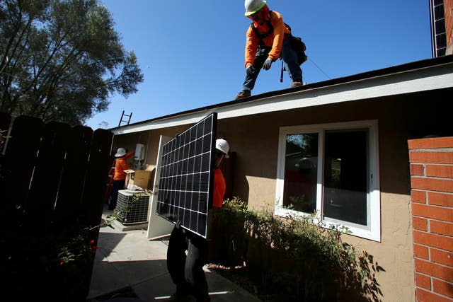 <p>Workers lift a solar panel onto a roof during a residential solar installation in Scripps Ranch, San Diego, California, US 14 October 2016</p>