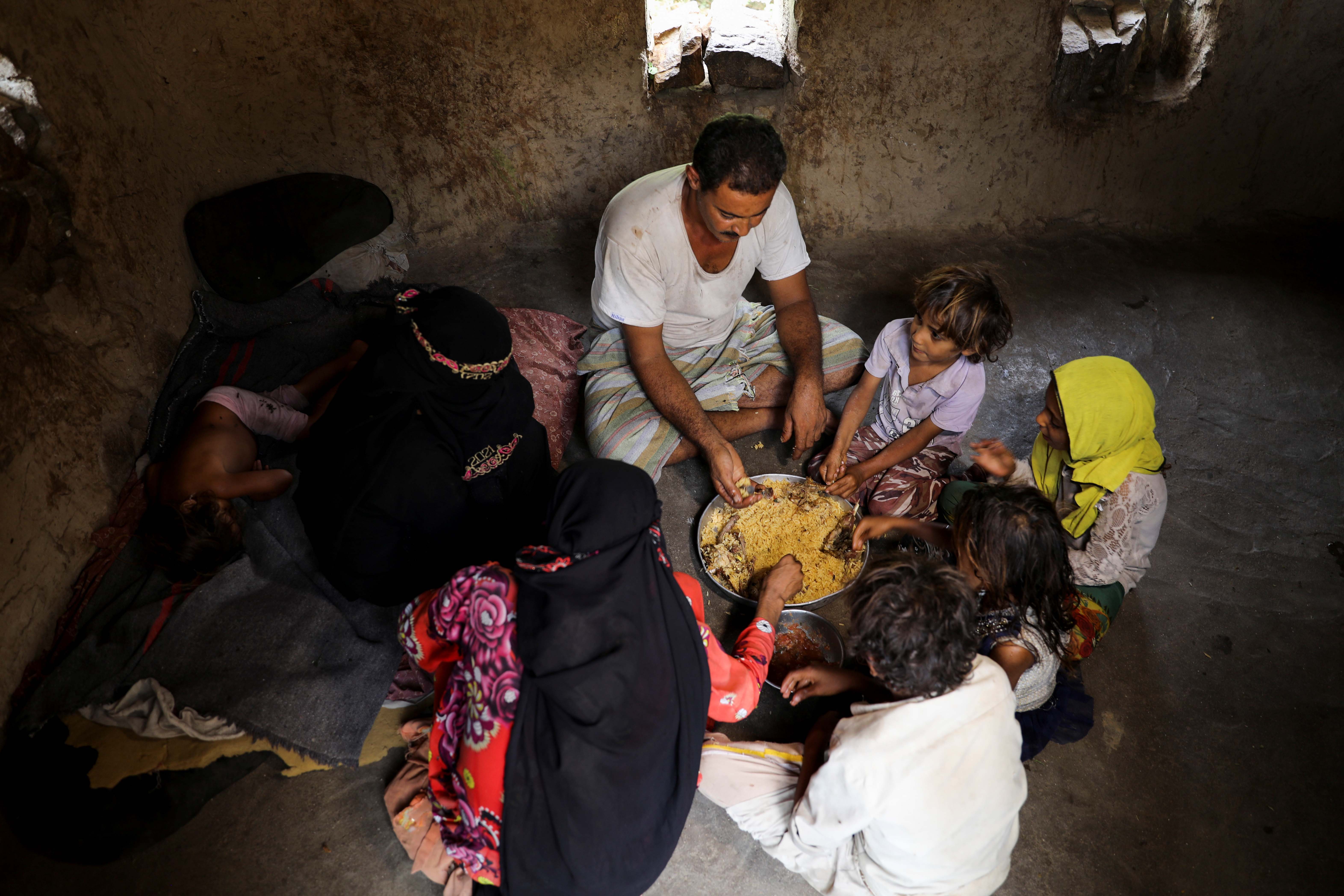 Ali al-Emadi, who works as a lumberjack, eats lunch with his family at their house in a village in Khamis Banisaad district of al-Mahweet province, Yemen
