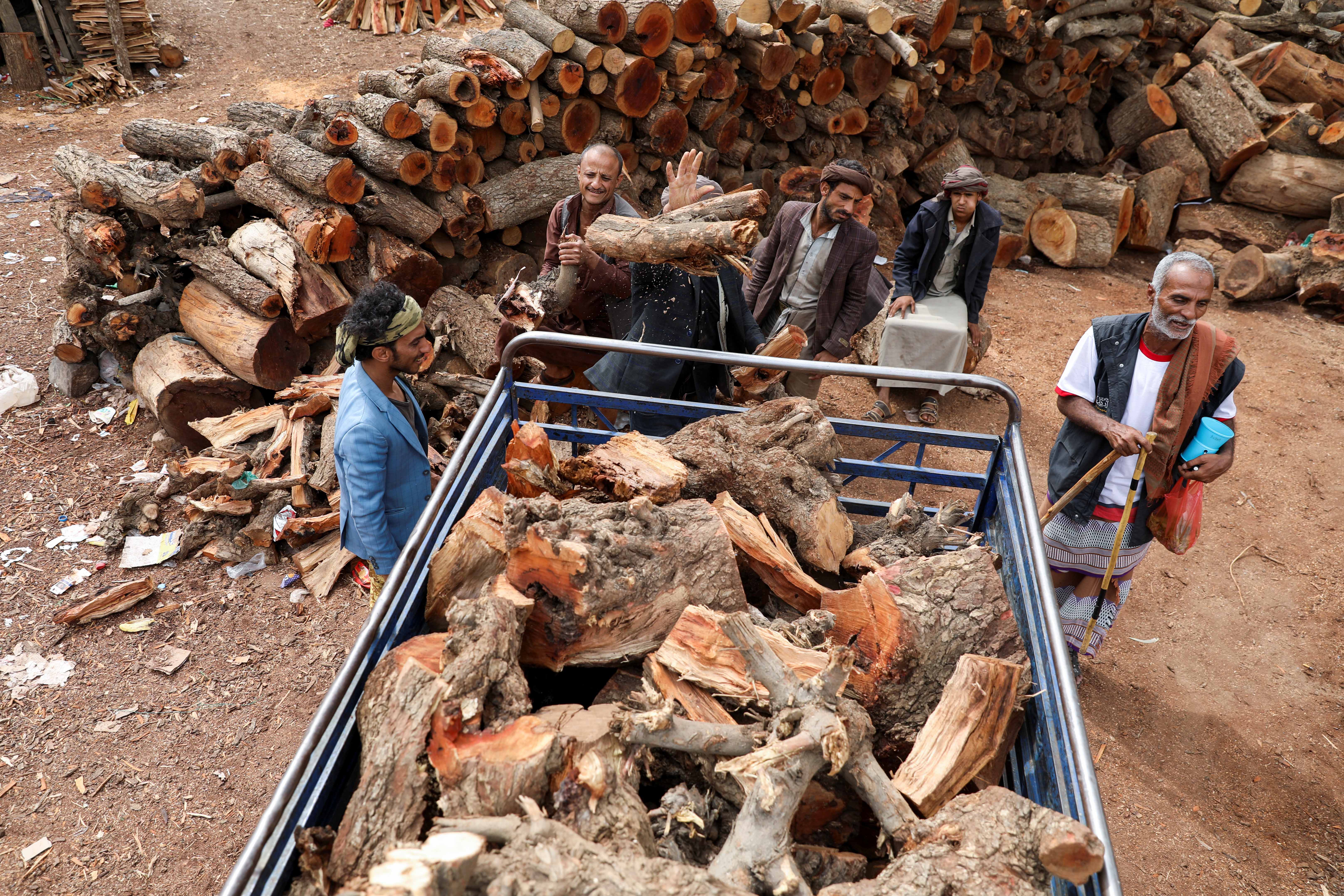 Vendors load wood onto a truck at a firewood market in Sana’a