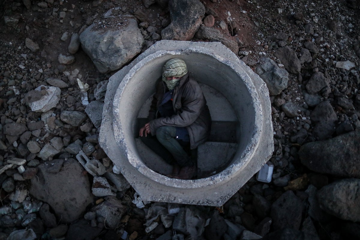 An Afghan boy hides inside a concrete sewer pipe