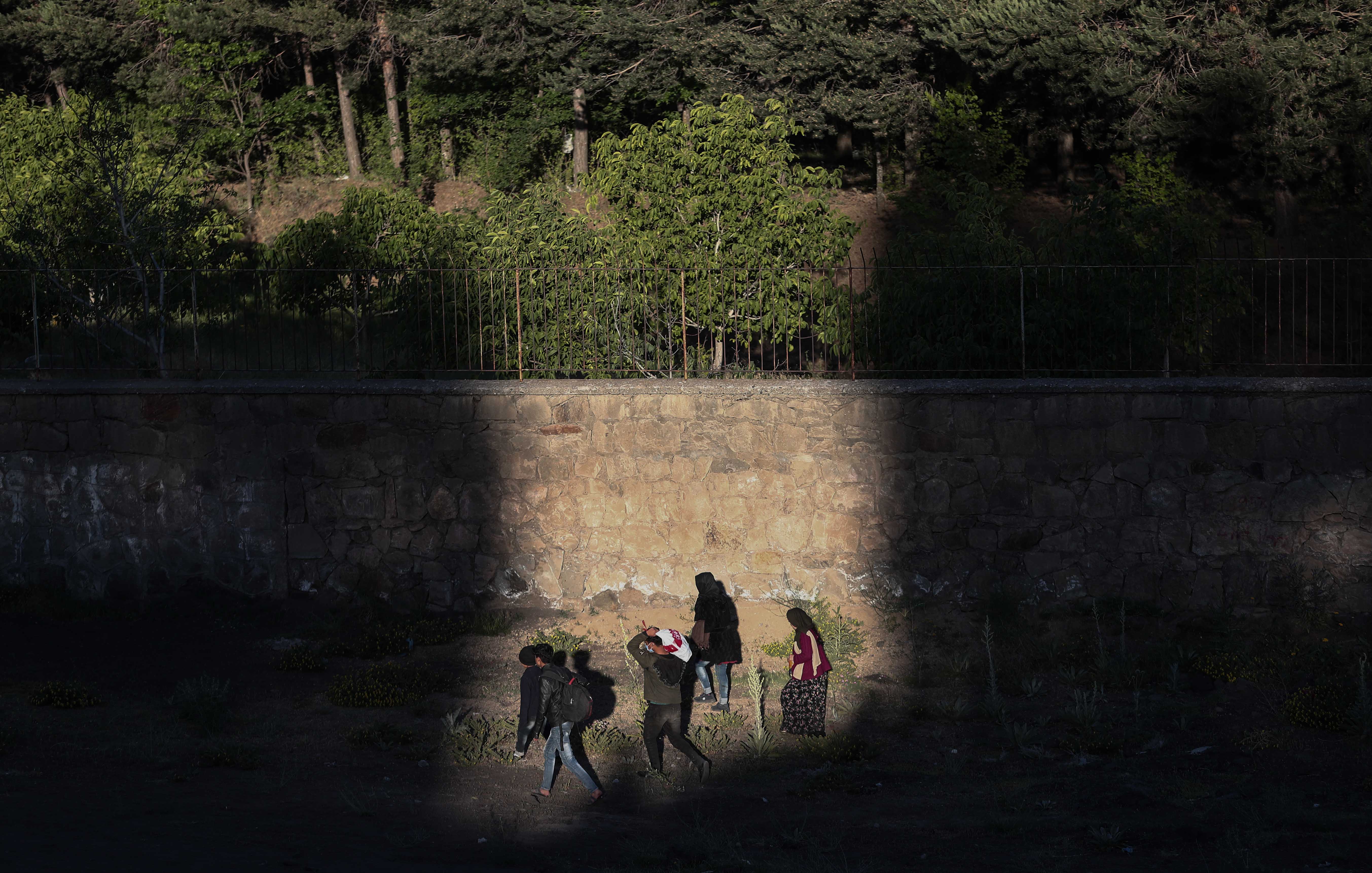 A group of people walk at sunset next to a railway in Van city