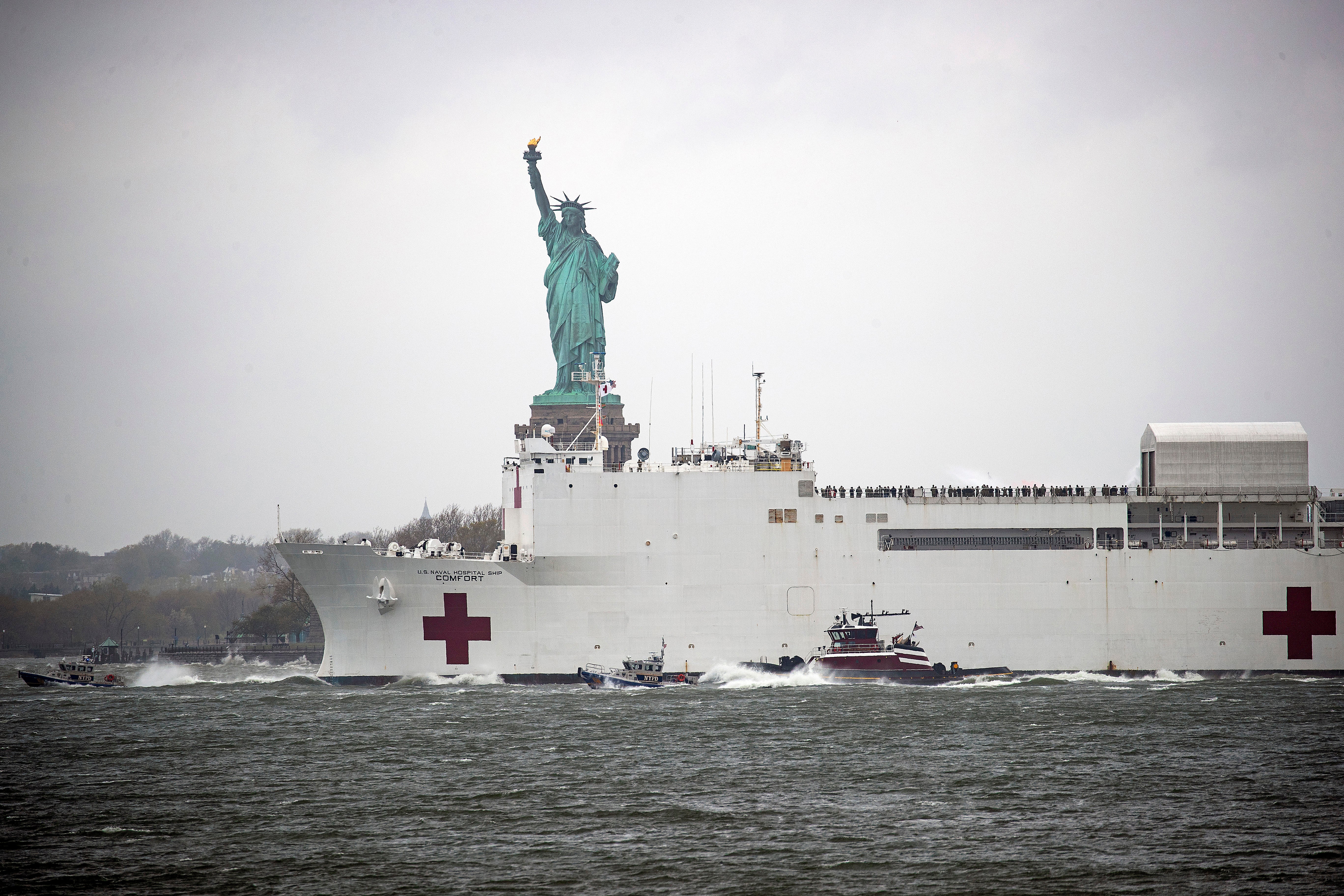 The USNS Comfort hospital ship exits the harbor in front of the Statue of Liberty as it heads back to Naval Station Norfolk in Virginia on April 30, 2020 in the Red Hook neighborhood of the Brooklyn borough of New York City.