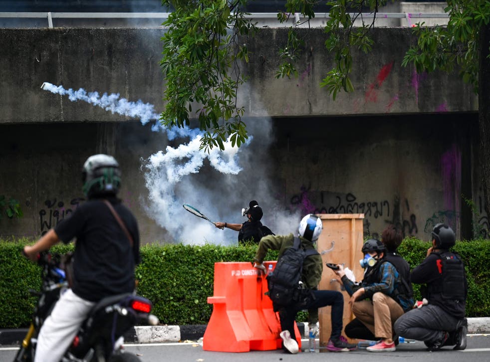 <p>A pro-democracy protester uses a tennis racket to return a tear gas canister to the police during a protest calling for the resignation of prime minister Prayuth Chan-ocha over the governments handling of the pandemic, in Bangkok on August 13, 2021</p>