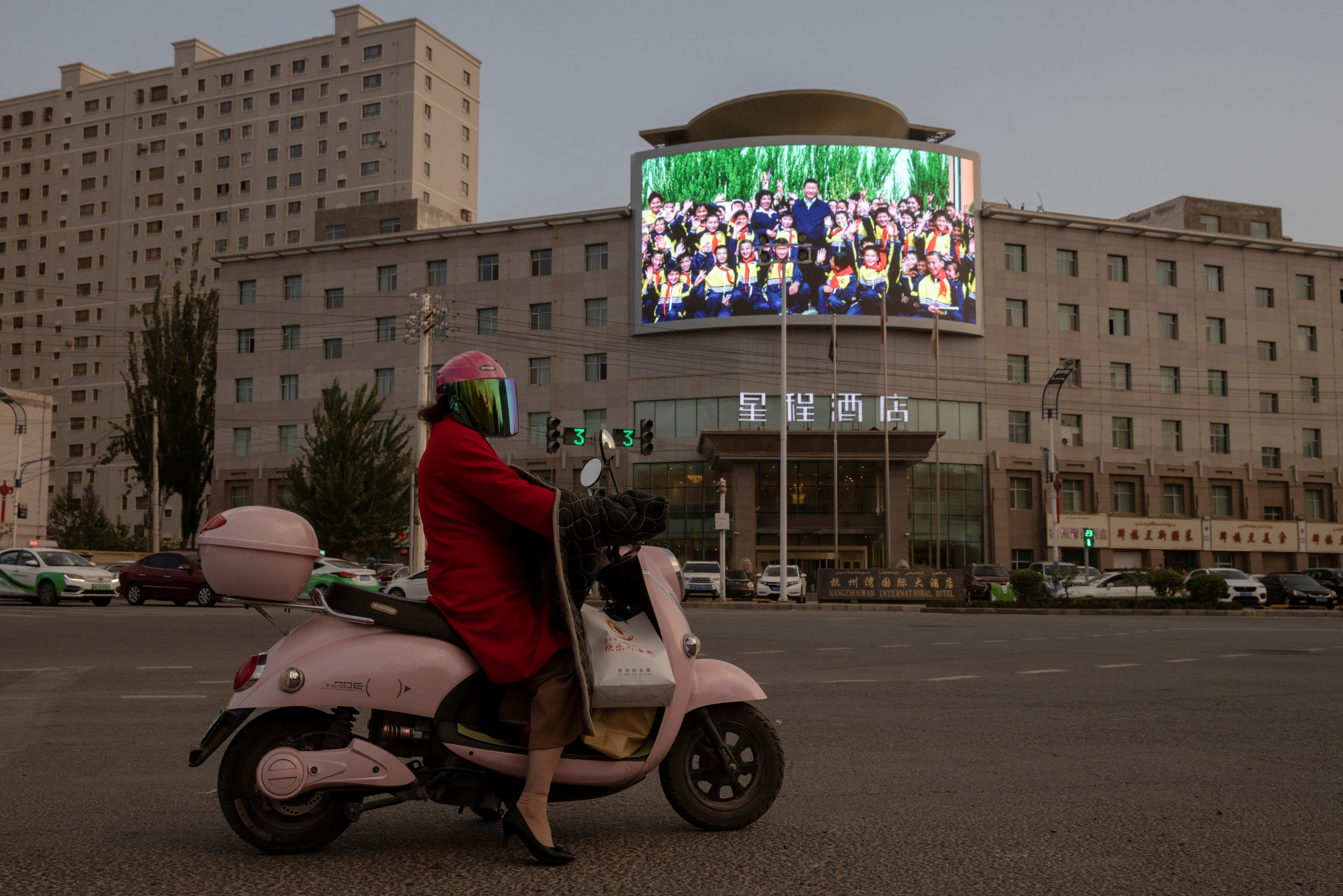 A screen shows President Xi Jinping among children at a traffic junction in Hotan, Xinjiang