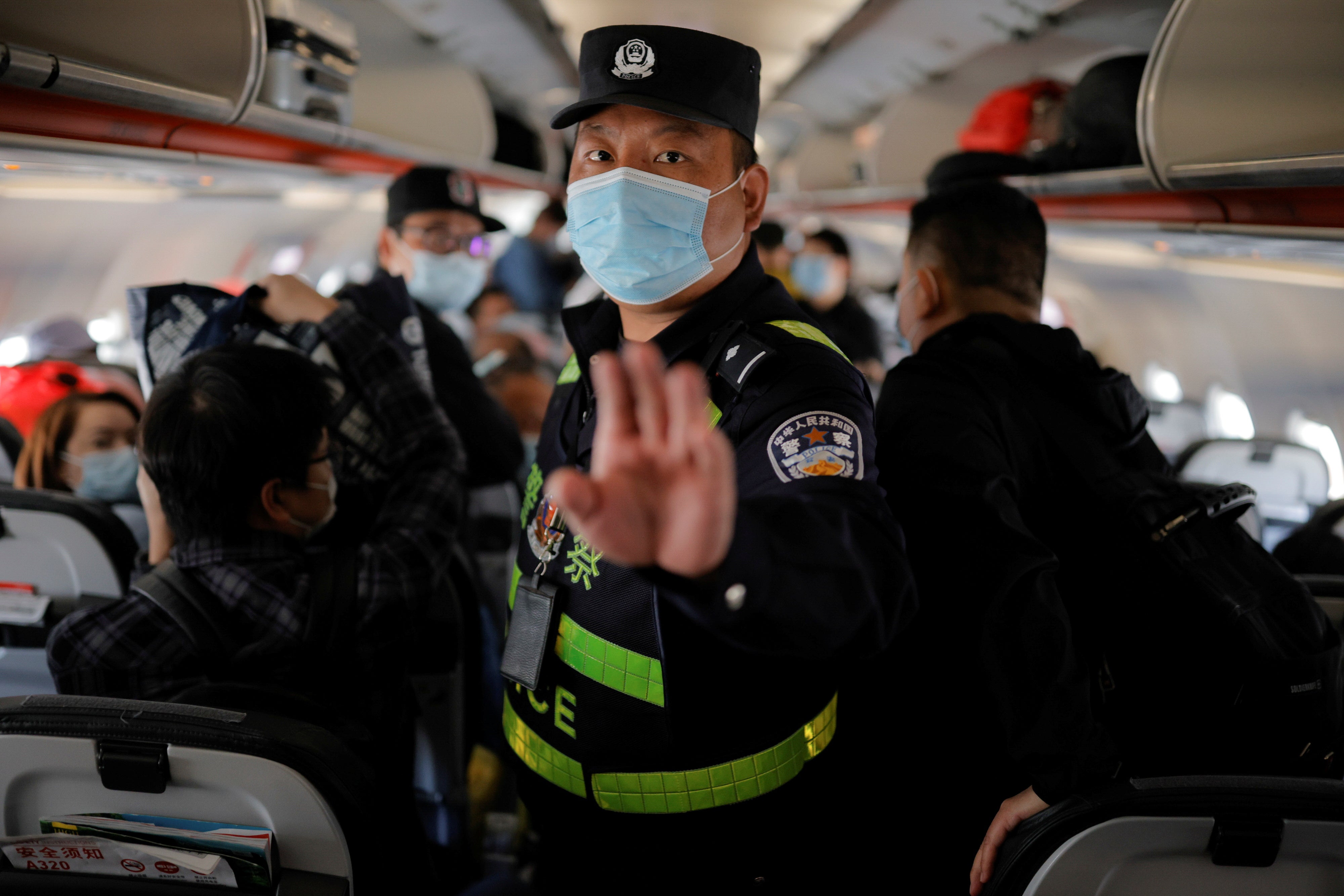 A police officer orders journalists off the plane before all others without explanation while parked on the Tarmac at Urumqi airport