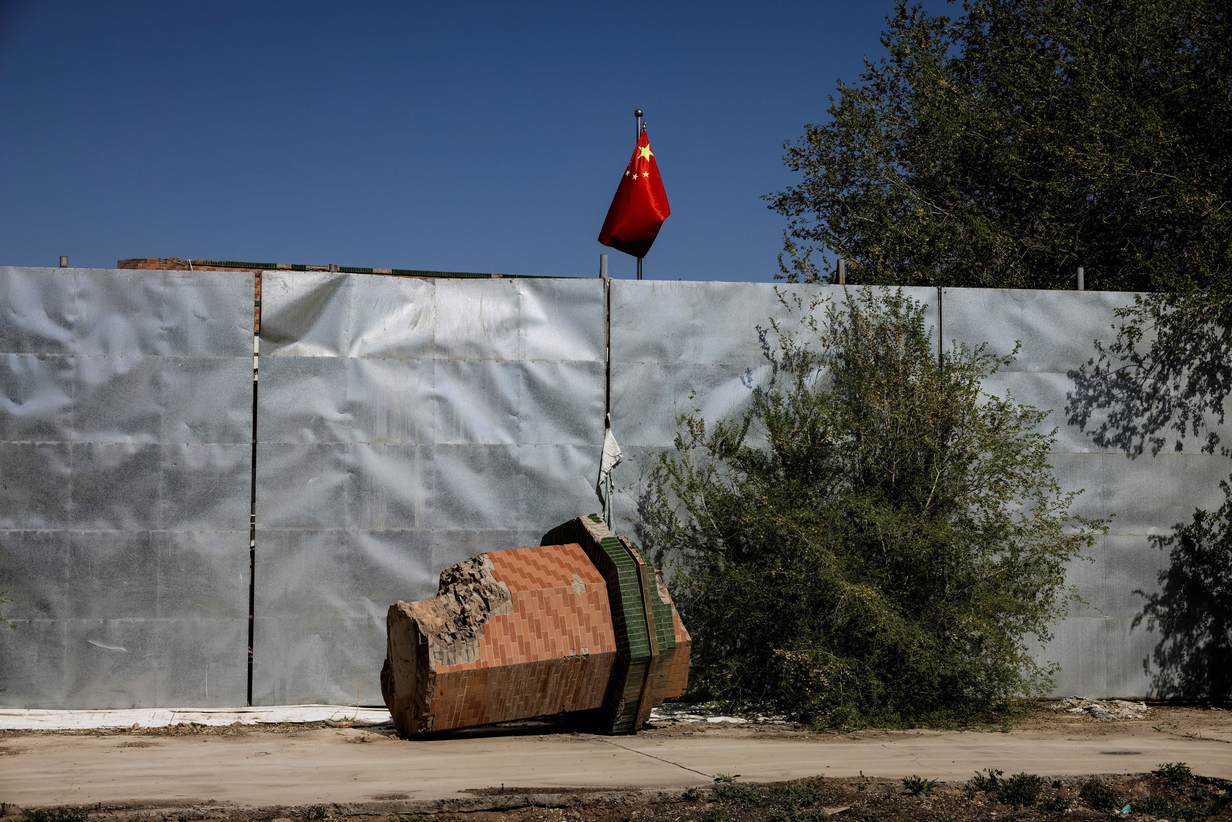 A broken-off minaret of Xinqu Mosque in Changji, outside Urumqi, lies near a Chinese national flag