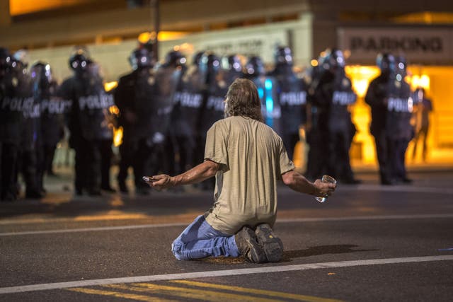 <p>A man kneels in the street as police officers advance upon demonstrators after a rally by President Donald Trump at the Phoenix Convention Center on August 22, 2017 in Phoenix, Arizona.</p>