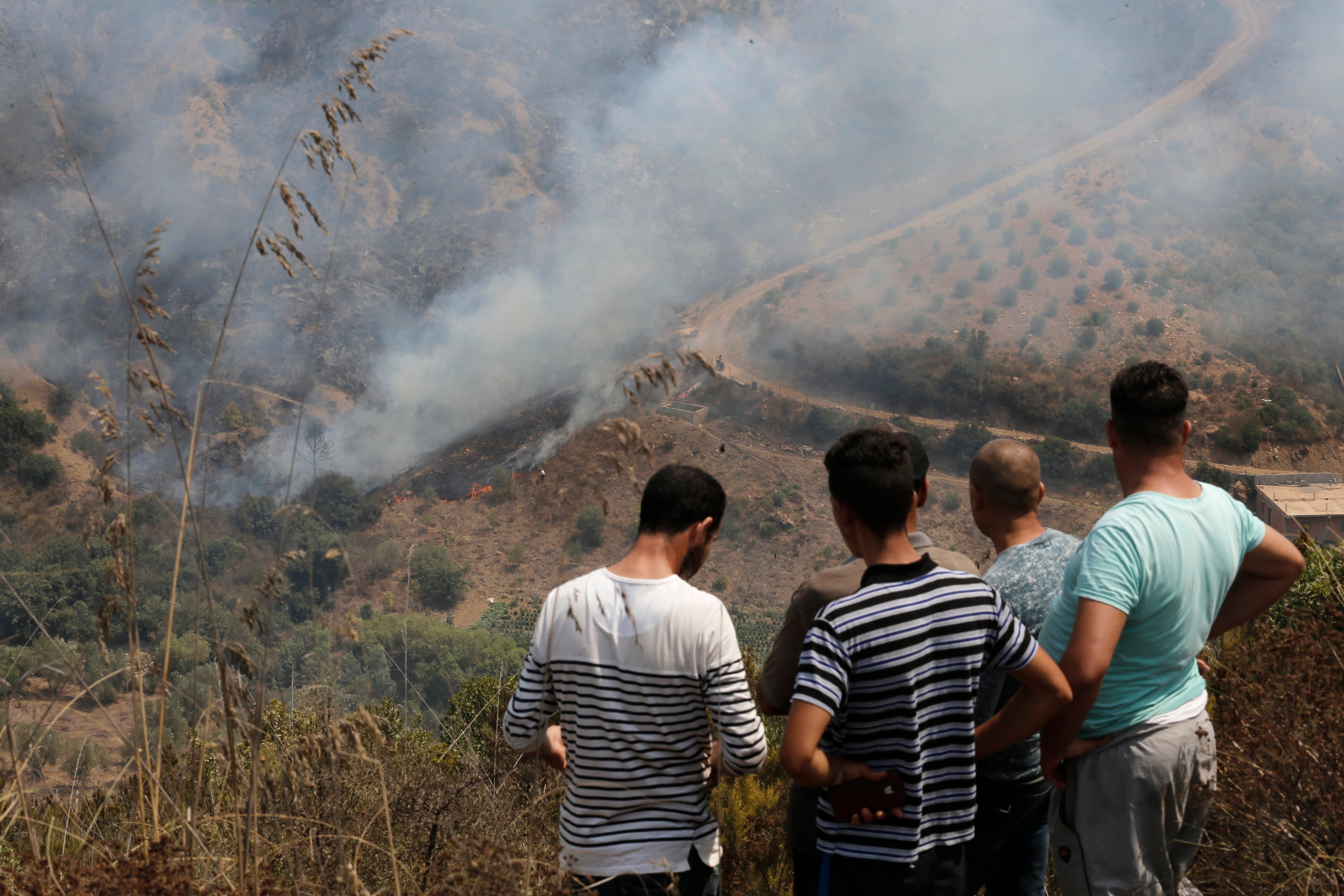 Residents watch a fire near the village of Toudja, in the Kabyle region, East of Algiers
