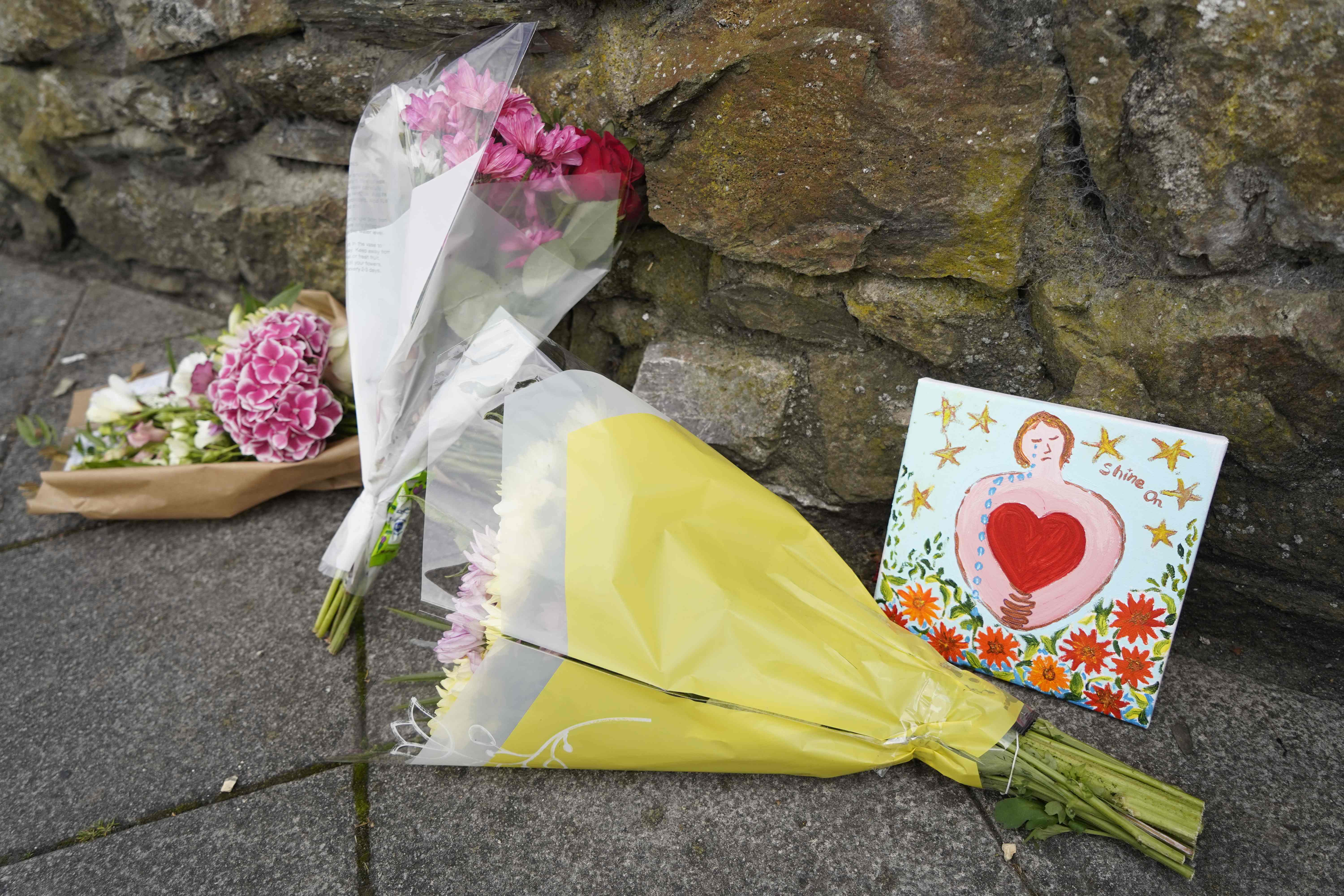 Floral tributes are placed on a pavement near the scene of the shooting