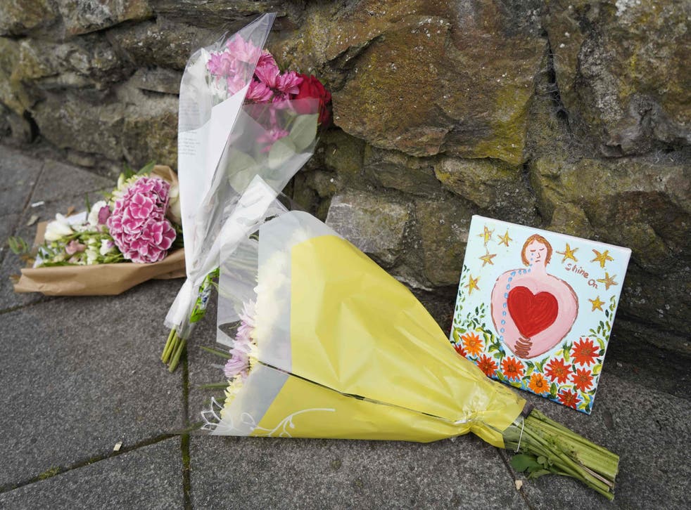 <p>Floral tributes are placed on a pavement near the scene of the shooting</p>